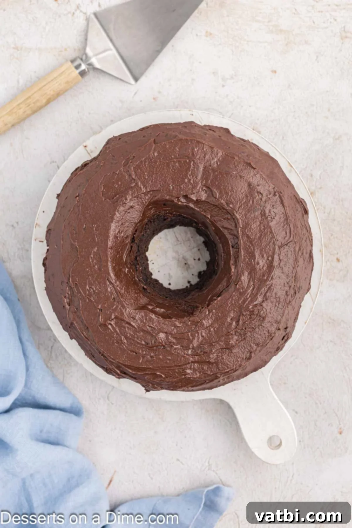 Decadent Chocolate Pound Cake 10 A perfectly baked and cooled chocolate pound cake sits on a platter, being generously covered with a rich, glossy chocolate glaze.