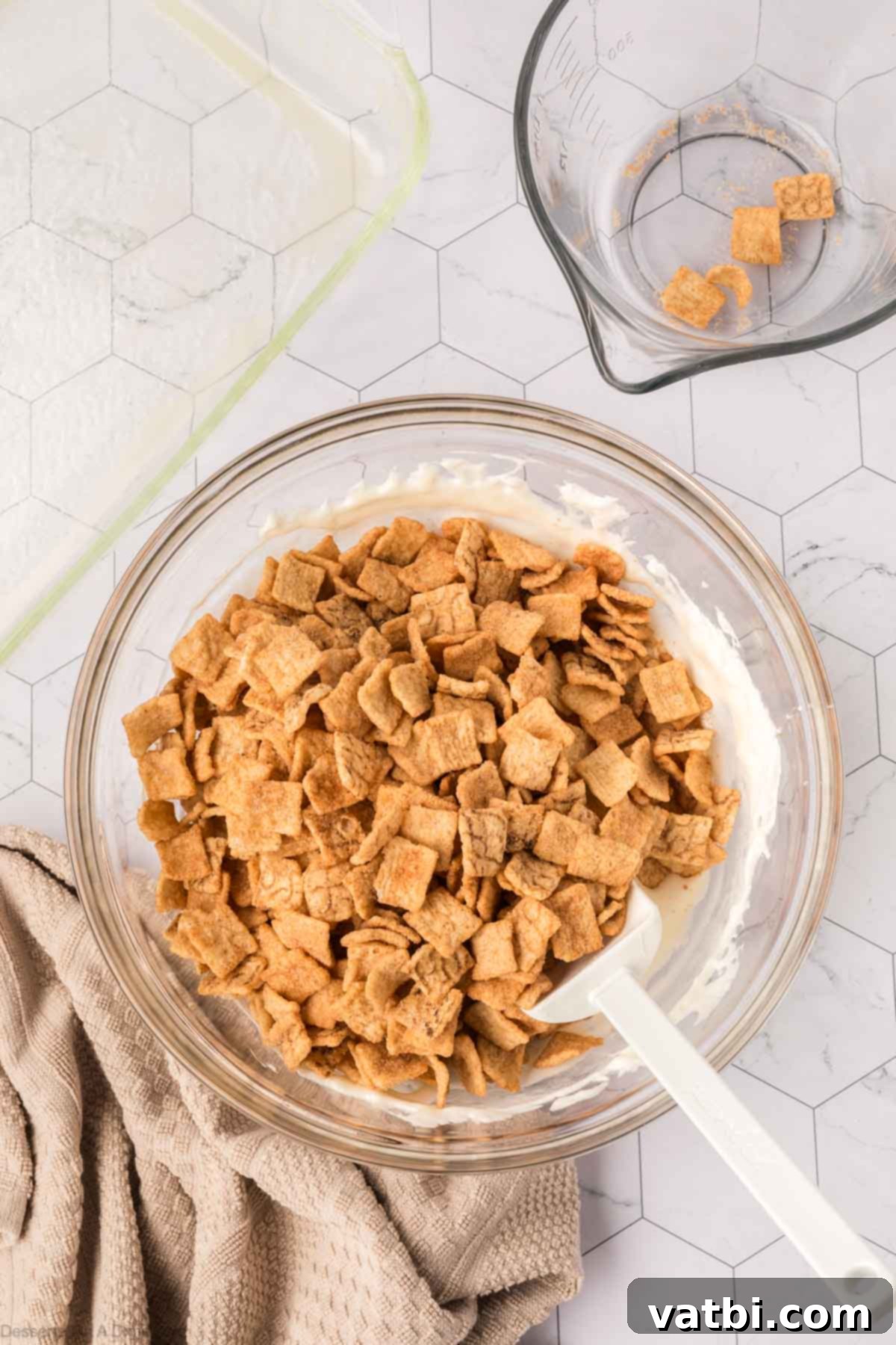 Irresistible Cinnamon Toast Crunch Bars 7 Cinnamon Toast Crunch cereal being gently folded into the melted marshmallow mixture.