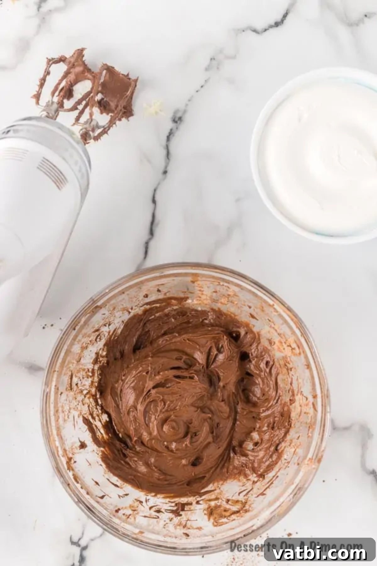 Chocolatey Fruit Indulgence 5 Unsweetened cocoa powder and vanilla extract being added to the creamy mixture of cream cheese and powdered sugar in a mixing bowl.