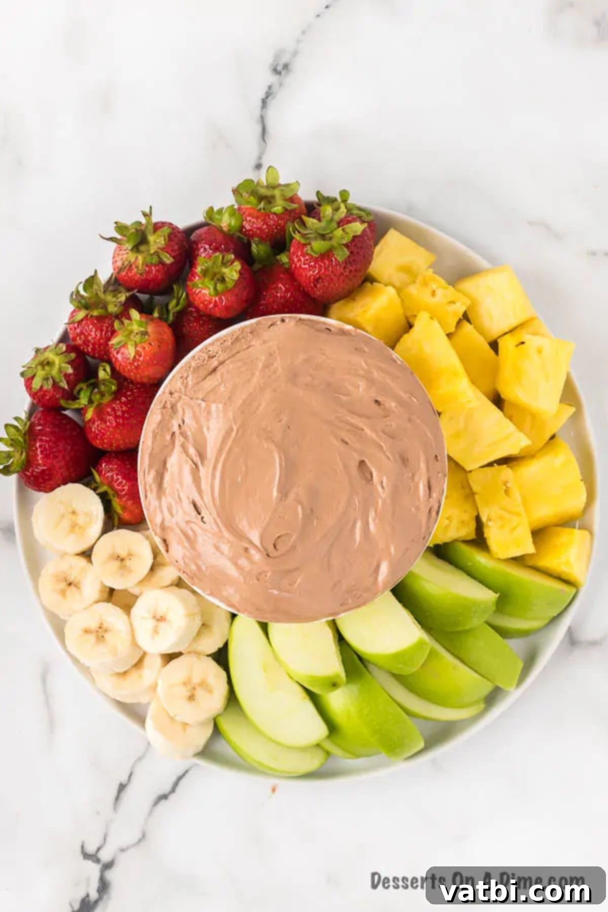 Chocolatey Fruit Indulgence 7 A serving bowl of chocolate fruit dip placed on a large platter, artfully arranged with a variety of fresh fruits and pretzels for dipping.