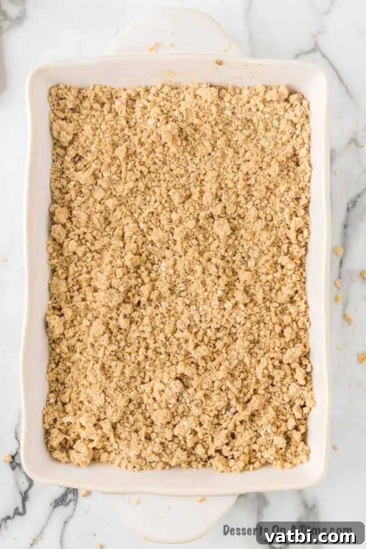 Harvest Caramel Apple Cheesecake Bars 13 The prepared streusel topping sprinkled generously and evenly over the spiced apple layer in the baking dish, creating a final crumbly top before baking.