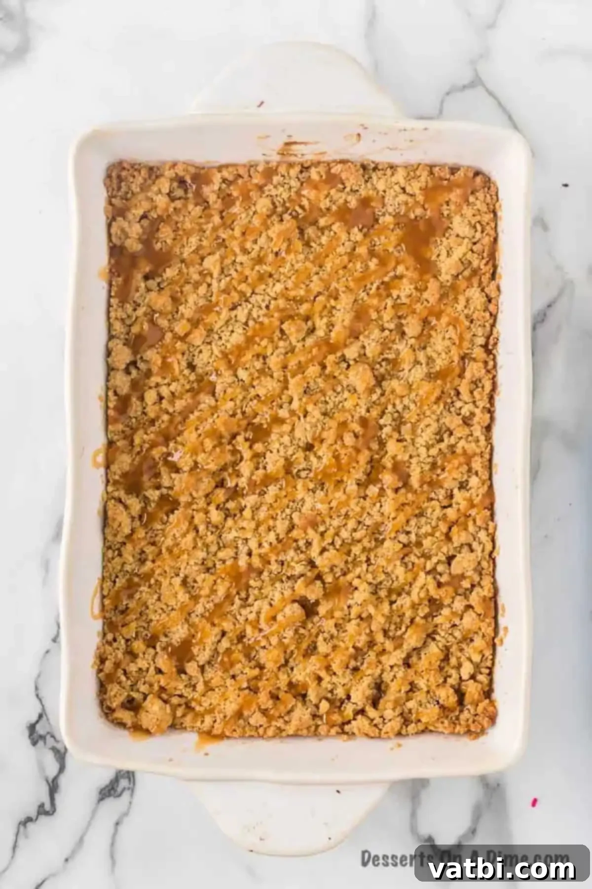 Harvest Caramel Apple Cheesecake Bars 14 Freshly baked Caramel Apple Cheesecake Bars in a 9x13 inch baking dish, cooling down with a glistening drizzle of caramel sauce over the streusel topping.