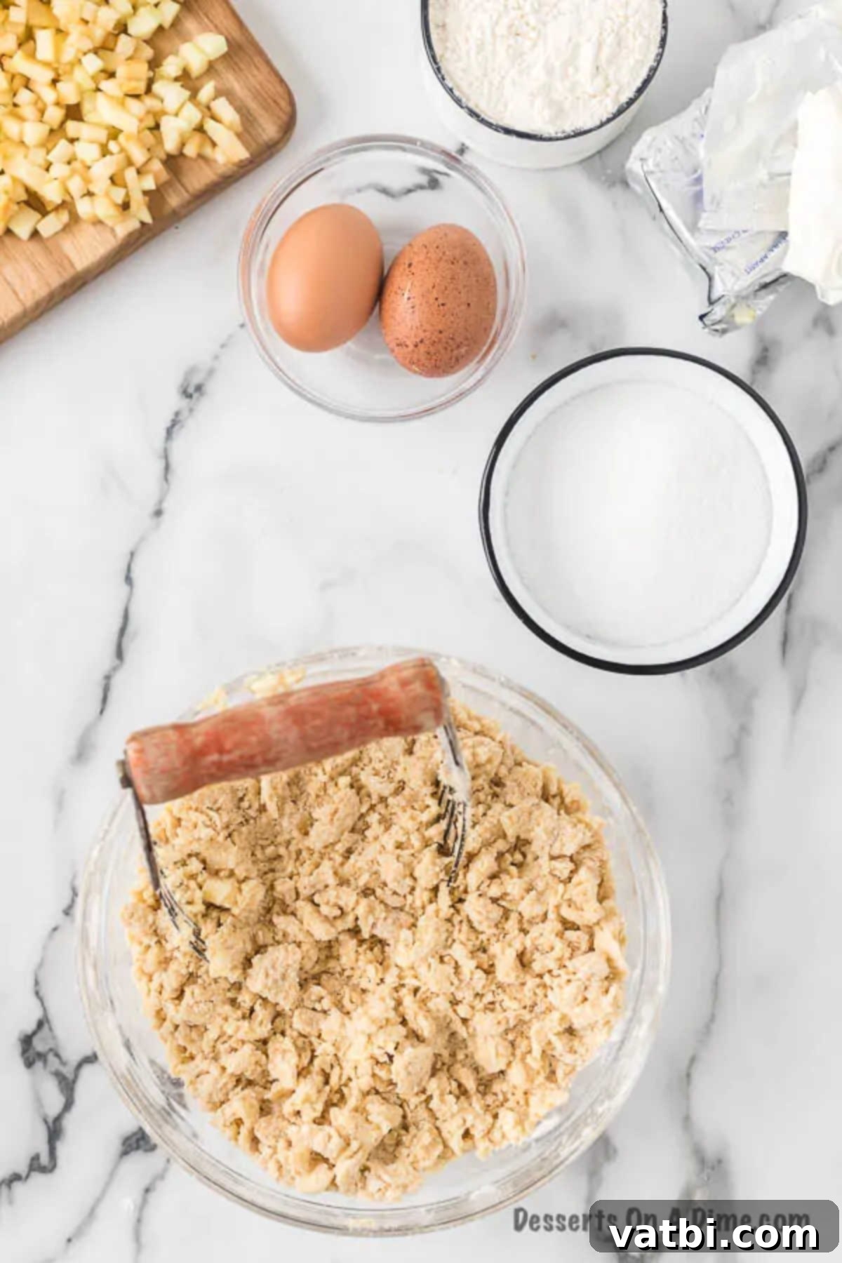 Harvest Caramel Apple Cheesecake Bars 5 Softened butter cubes being cut into a mixture of flour and brown sugar in a bowl using a pastry blender, forming a crumbly texture for the crust.