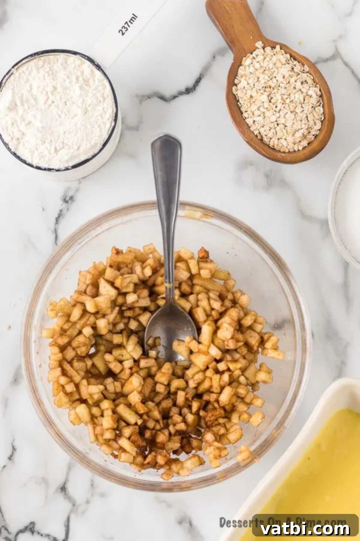 Harvest Caramel Apple Cheesecake Bars 10 A small bowl containing finely chopped Granny Smith apples, granulated sugar, ground cinnamon, and ground nutmeg, mixed together to create the spiced apple layer.