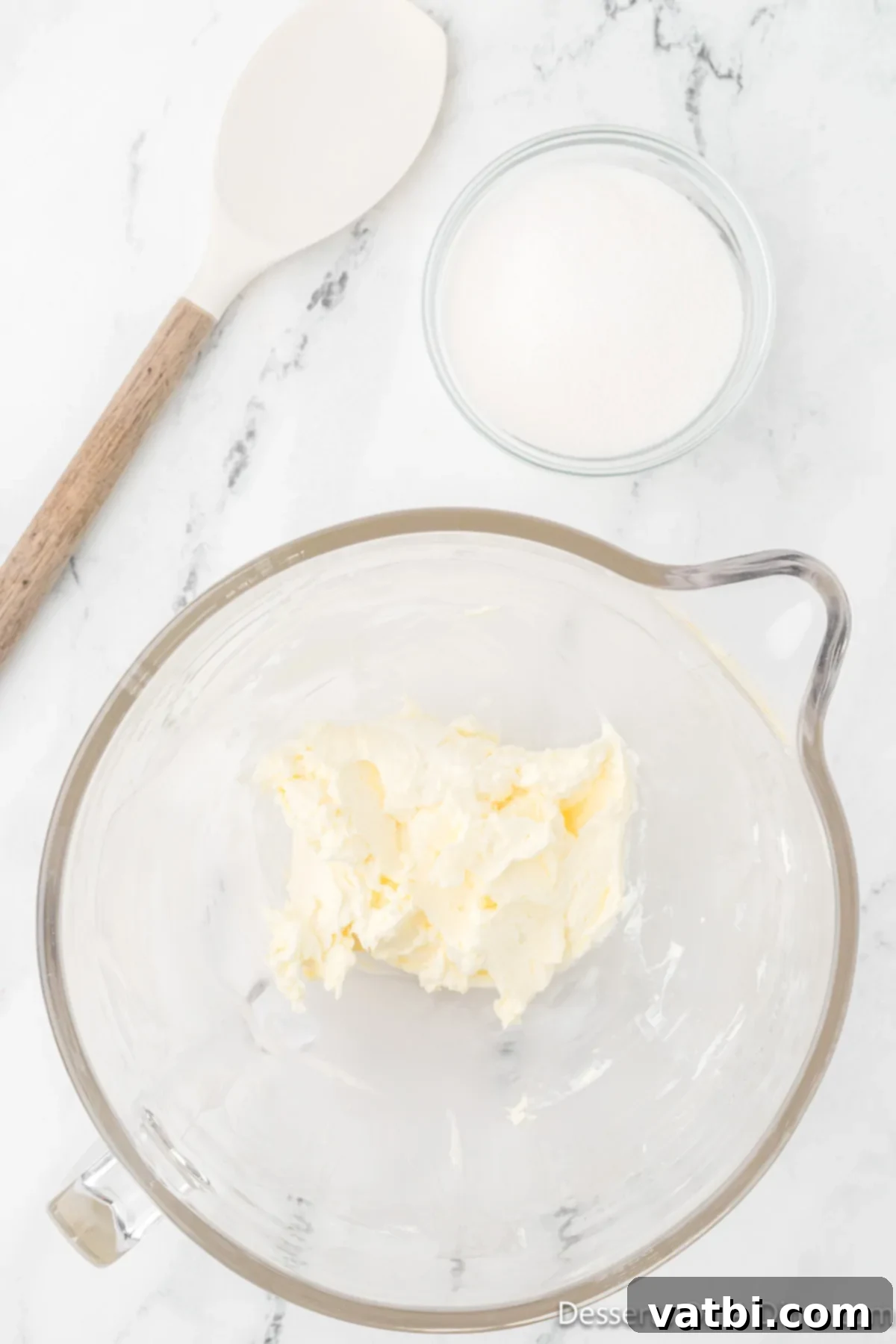 Cream cheese and butter being creamed together in a stand mixer.
