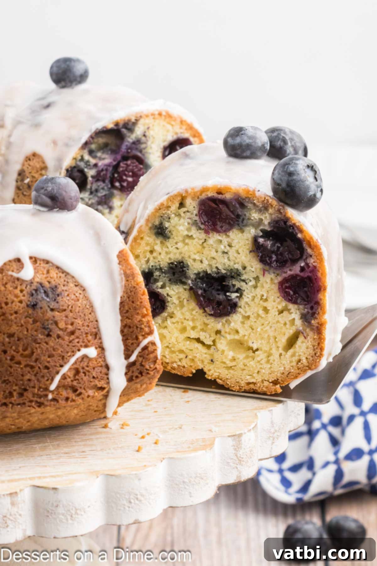 Blueberry Crown Cake 2 A perfectly sliced Blueberry Bundt Cake, revealing its moist crumb and scattered blueberries, adorned with a sweet glaze and fresh berries on top, ready to be enjoyed.