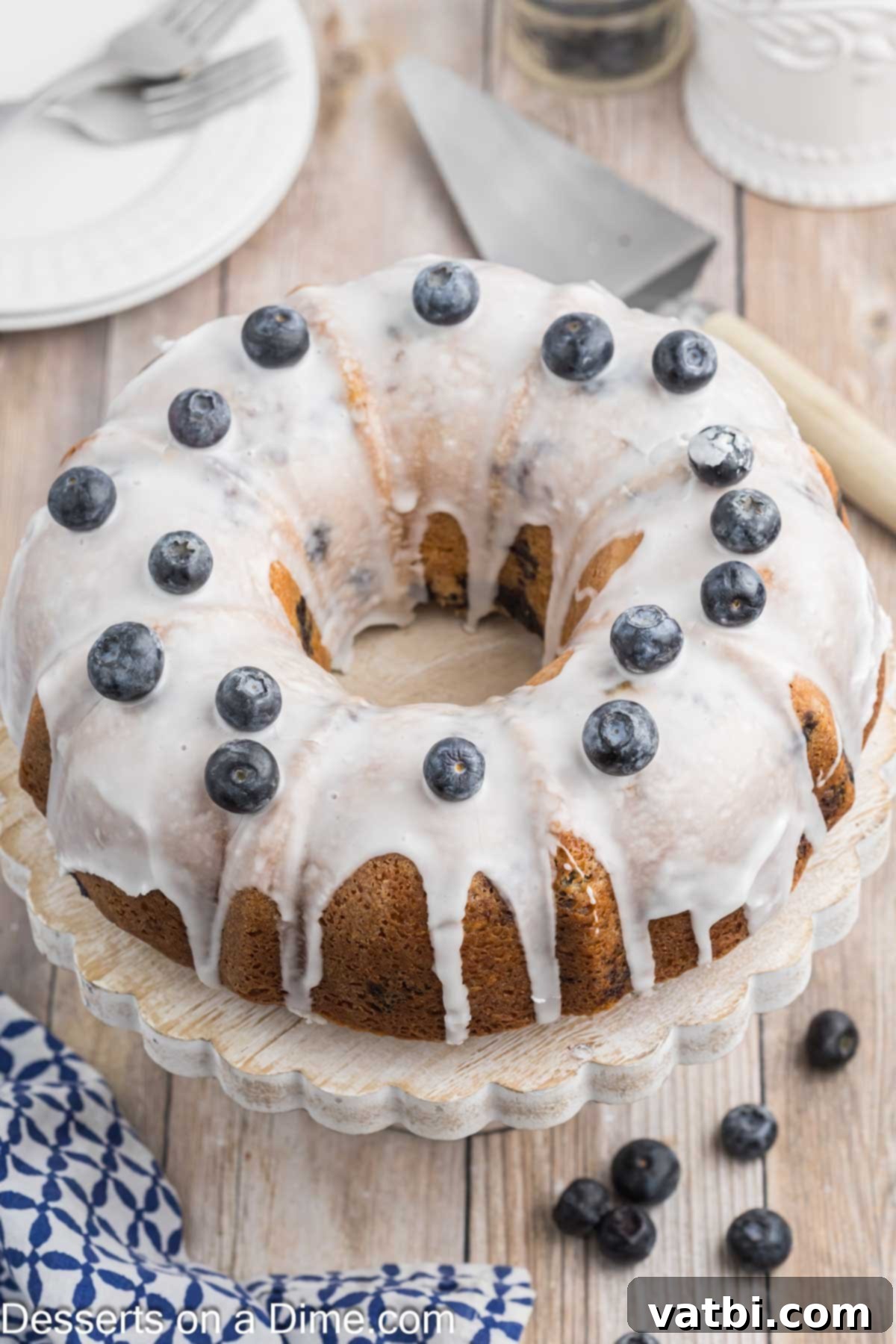 Blueberry Crown Cake 8 A beautiful Blueberry Bundt Cake, freshly glazed and generously garnished with vibrant fresh blueberries, poised elegantly on a cake stand, ready for slicing and serving.