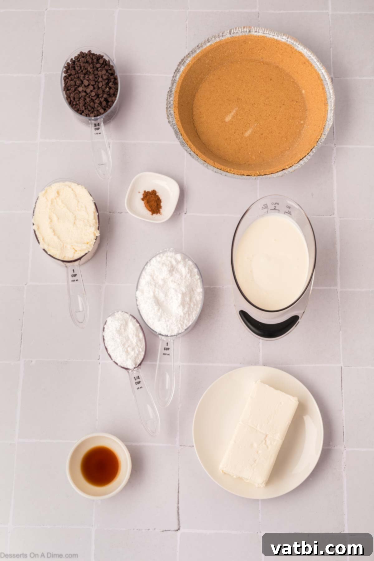 Decadent Cannoli Pie 3 All ingredients for cannoli pie laid out: cream cheese, vanilla extract, heavy cream, powdered sugar, whole milk ricotta, cinnamon, mini chocolate chips, and a graham cracker crust.