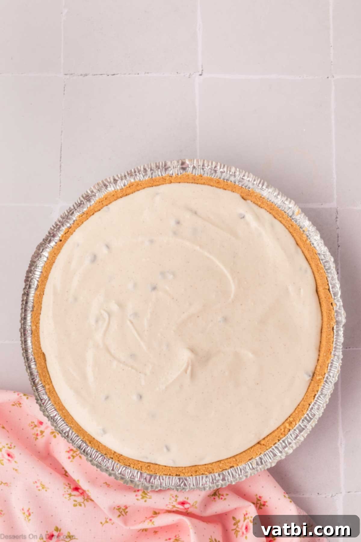 Decadent Cannoli Pie 8 The creamy cannoli pie filling being spread evenly into a graham cracker pie crust.