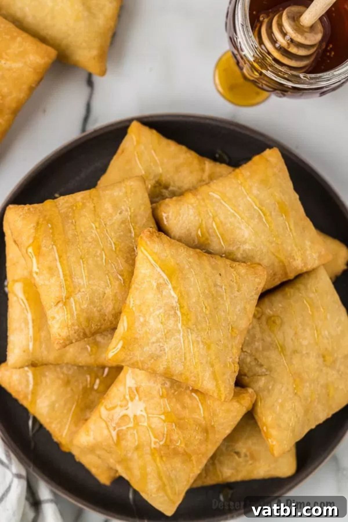 Golden & Fluffy Sopapillas: The Perfect Sweet Treat 2 Homemade sopapillas on a plate, golden brown and ready to be drizzled with honey.