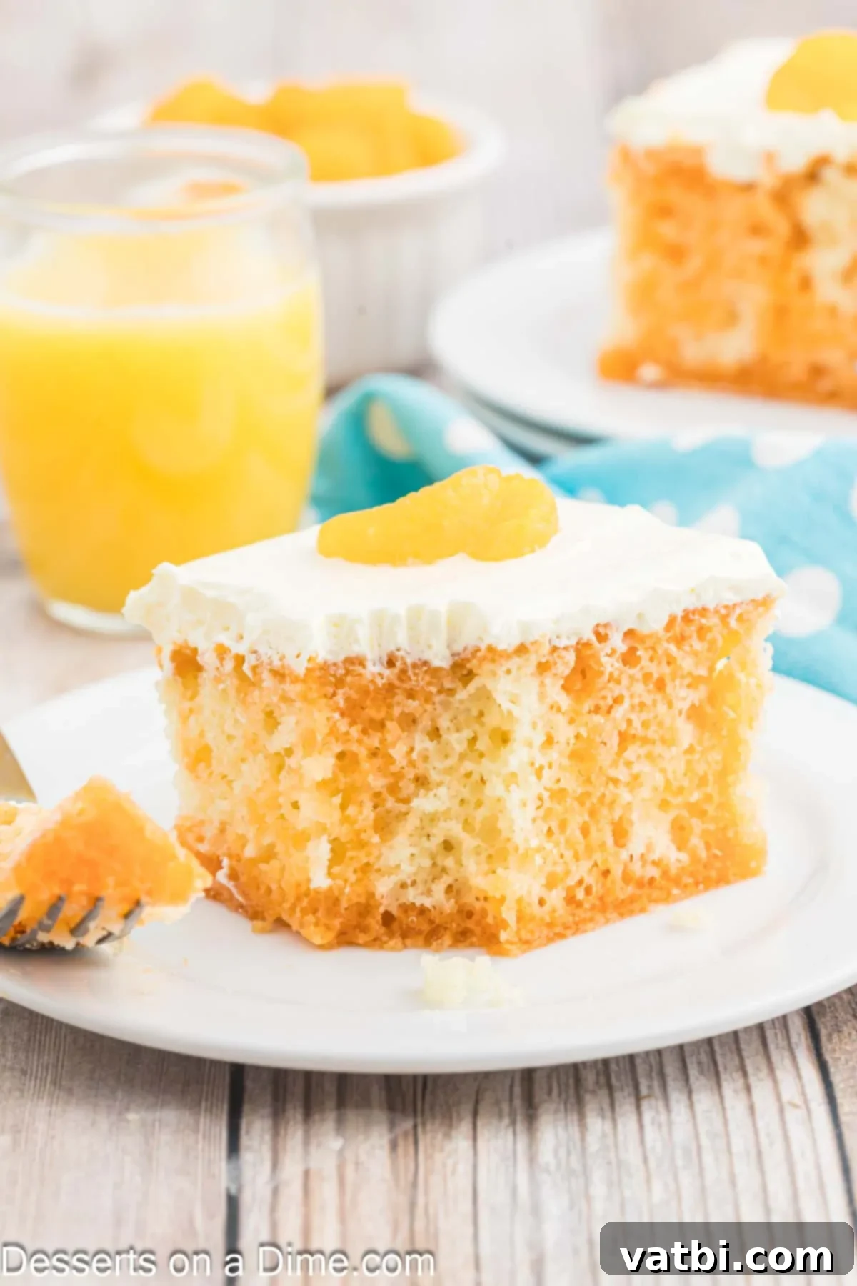 Orange Creamsicle Cake 2 Orange Dreamsicle cake cut into slices on a plate, showcasing its moist texture and vibrant orange-white layers.