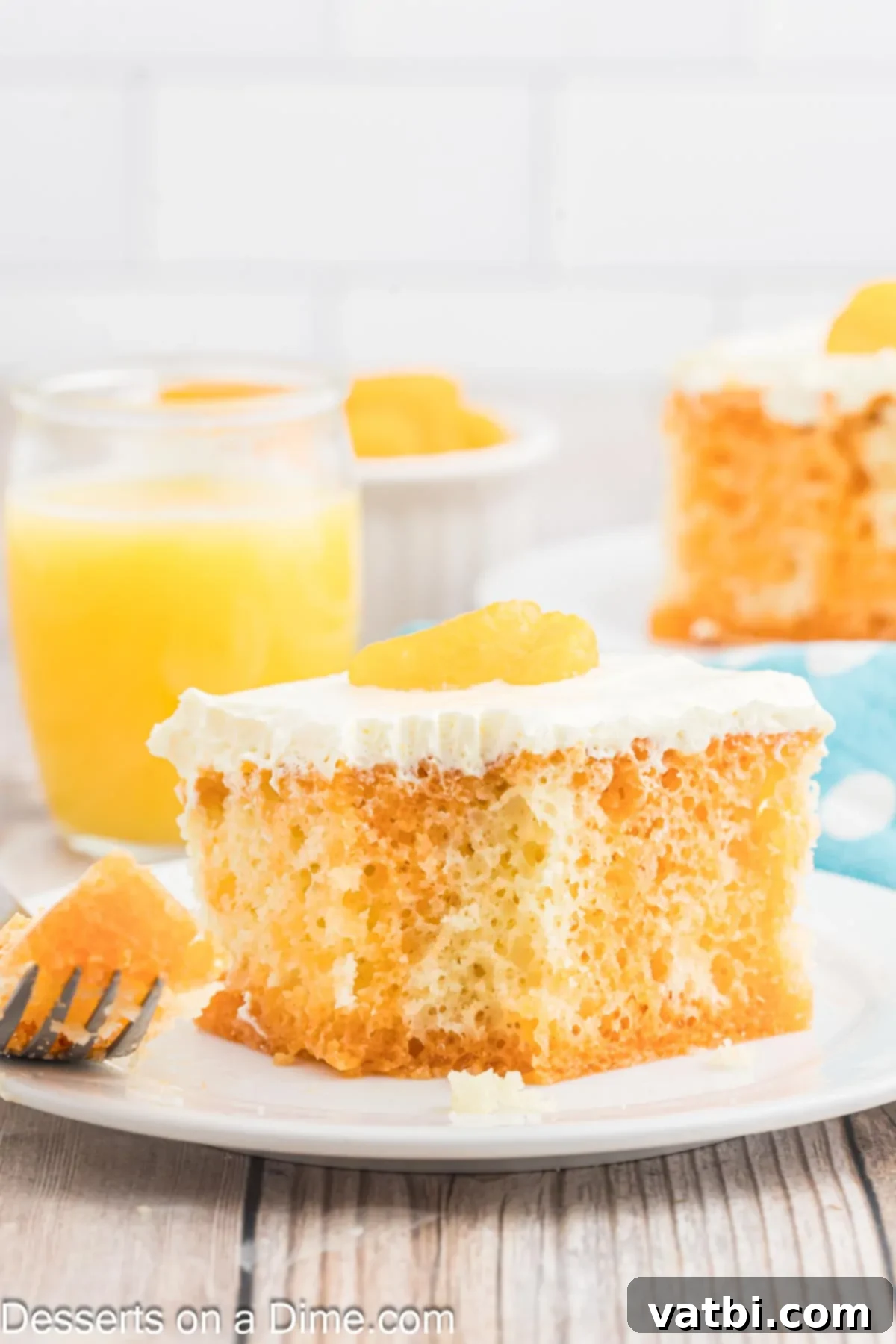 Orange Creamsicle Cake 12 A slice of Orange Creamsicle Cake on a plate, showing the moist cake, orange gelatin infusion, and creamy white frosting, garnished with mandarin oranges.