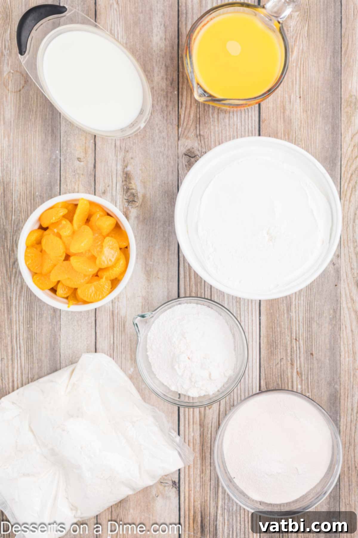 Orange Creamsicle Cake 3 A selection of ingredients for Orange Creamsicle Cake, including a white cake mix box, orange juice, orange jello, vanilla pudding mix, milk, cool whip, and canned mandarin oranges.
