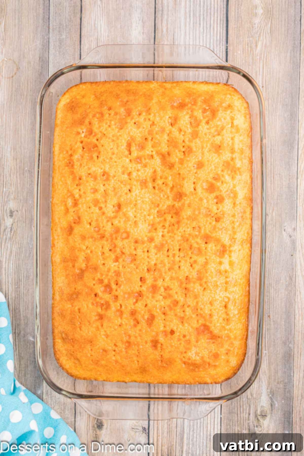 Orange Creamsicle Cake 8 Orange gelatin mixture poured over the poked cake, soaking into the holes.