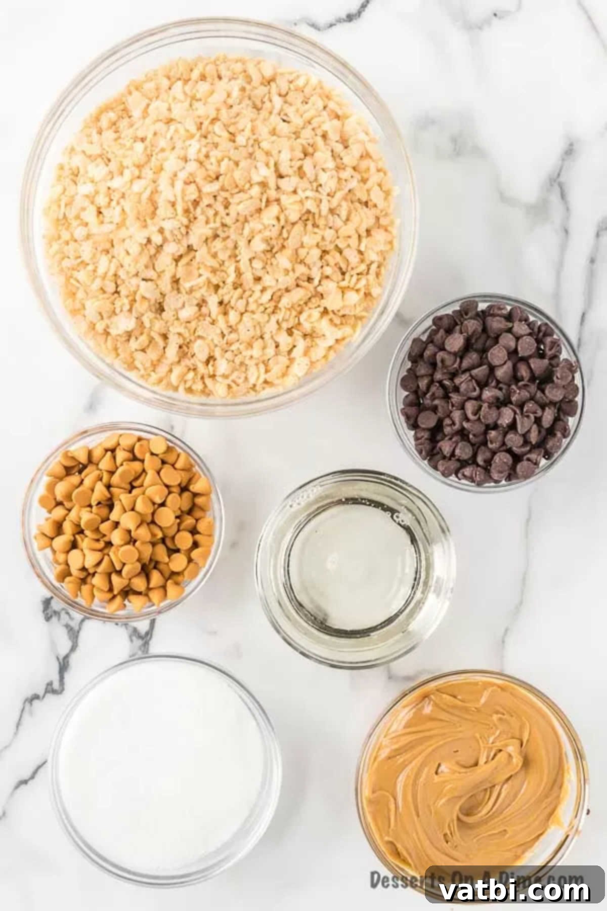 Individual ingredients for Scotcheroos displayed: a bowl of Rice Krispies cereal, a jar of peanut butter, a bag of granulated sugar, a bottle of light corn syrup, a bag of semi-sweet chocolate chips, and a bag of butterscotch chips.
