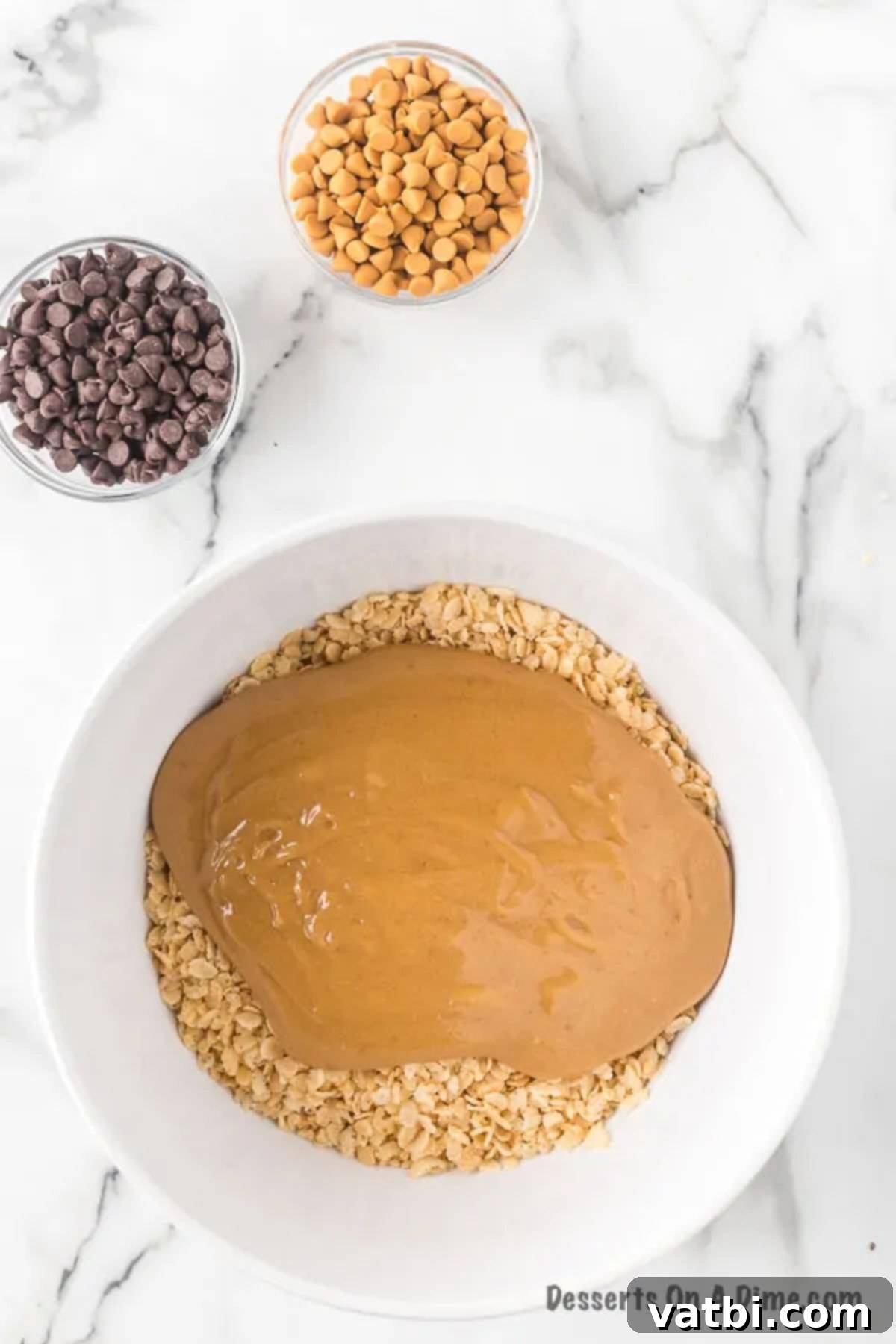Large mixing bowl containing Rice Krispies cereal covered with the warm peanut butter and corn syrup mixture, being thoroughly combined.
