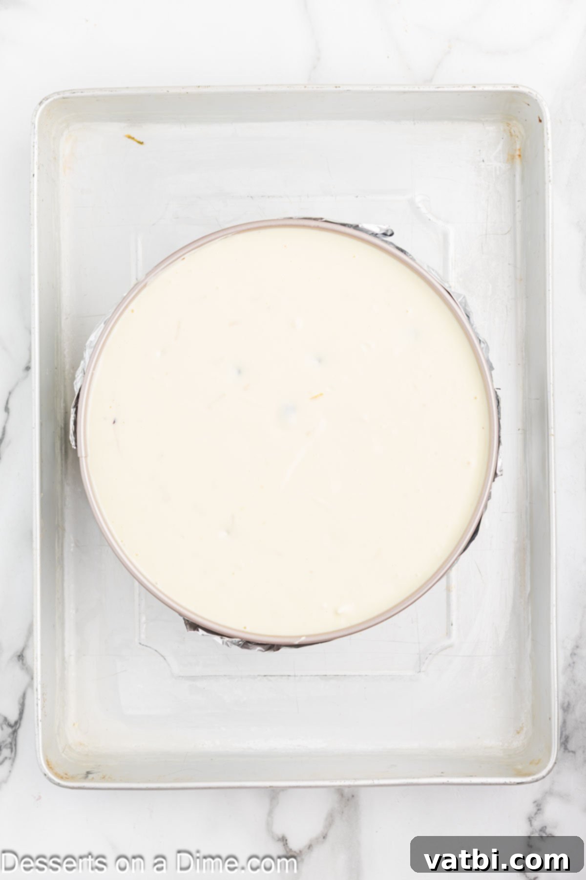 Luscious Lemon Blueberry Cheesecake 7 Cheesecake mixture poured into the pan, which is then placed in a water bath inside a larger roasting pan.