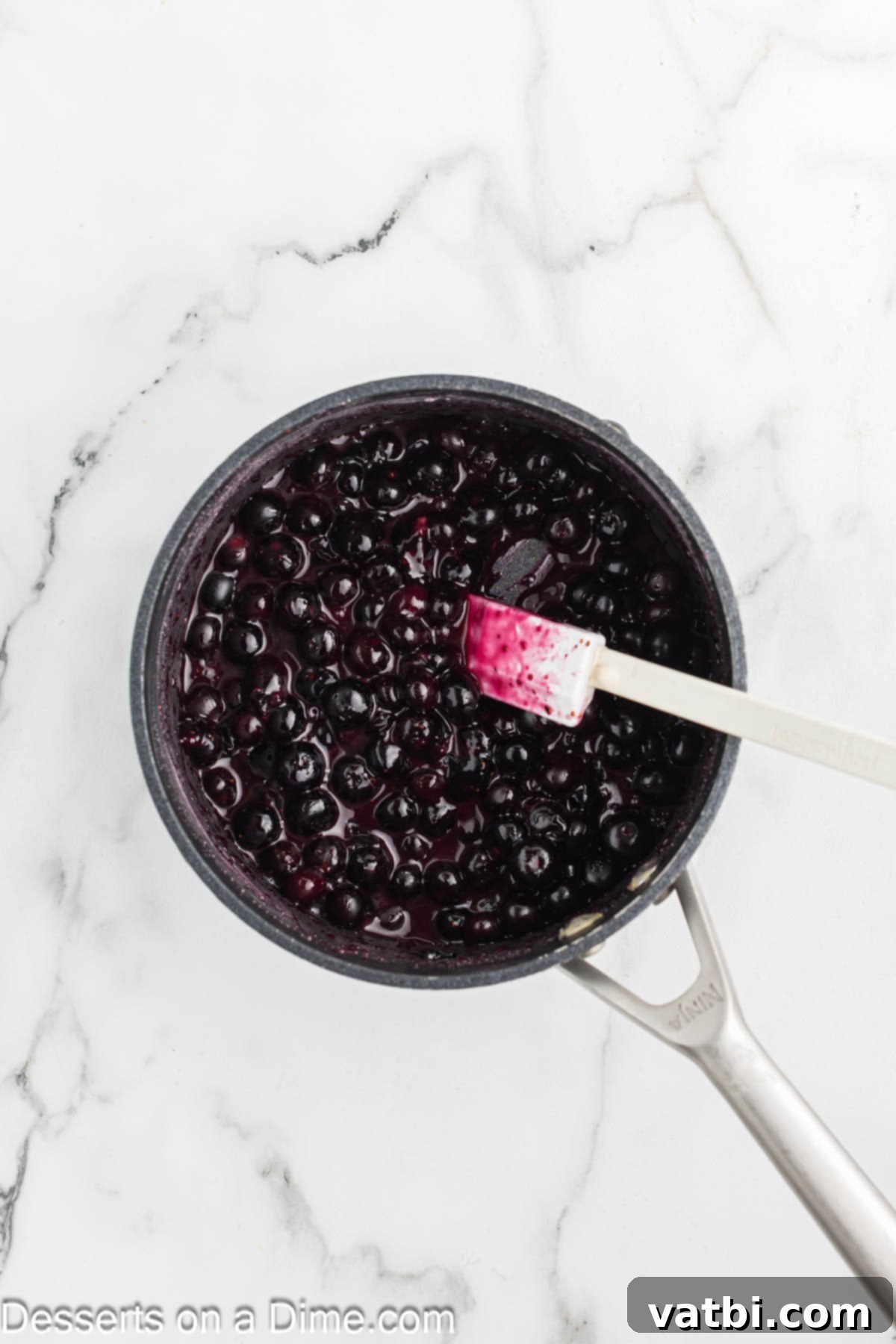Luscious Lemon Blueberry Cheesecake 10 Blueberry topping simmering in a saucepan, thickening into a glossy sauce.