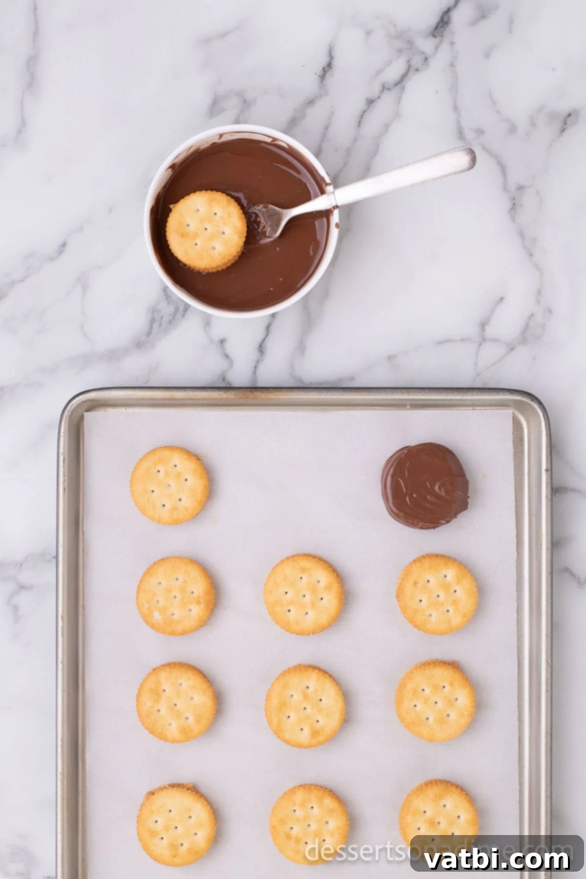 Sweet and Salty Chocolate Ritz Bites 7 Freshly coated peanut butter and Ritz cracker sandwiches, gleaming with melted chocolate, placed on wax paper on a baking sheet to cool and set.