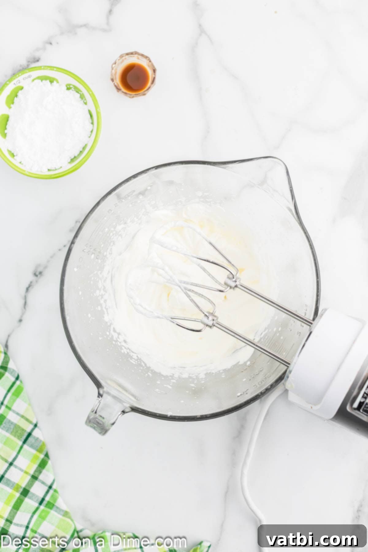 Key Lime Cheesecake 9 Whipped cream being beaten in a mixing bowl with an electric mixer.