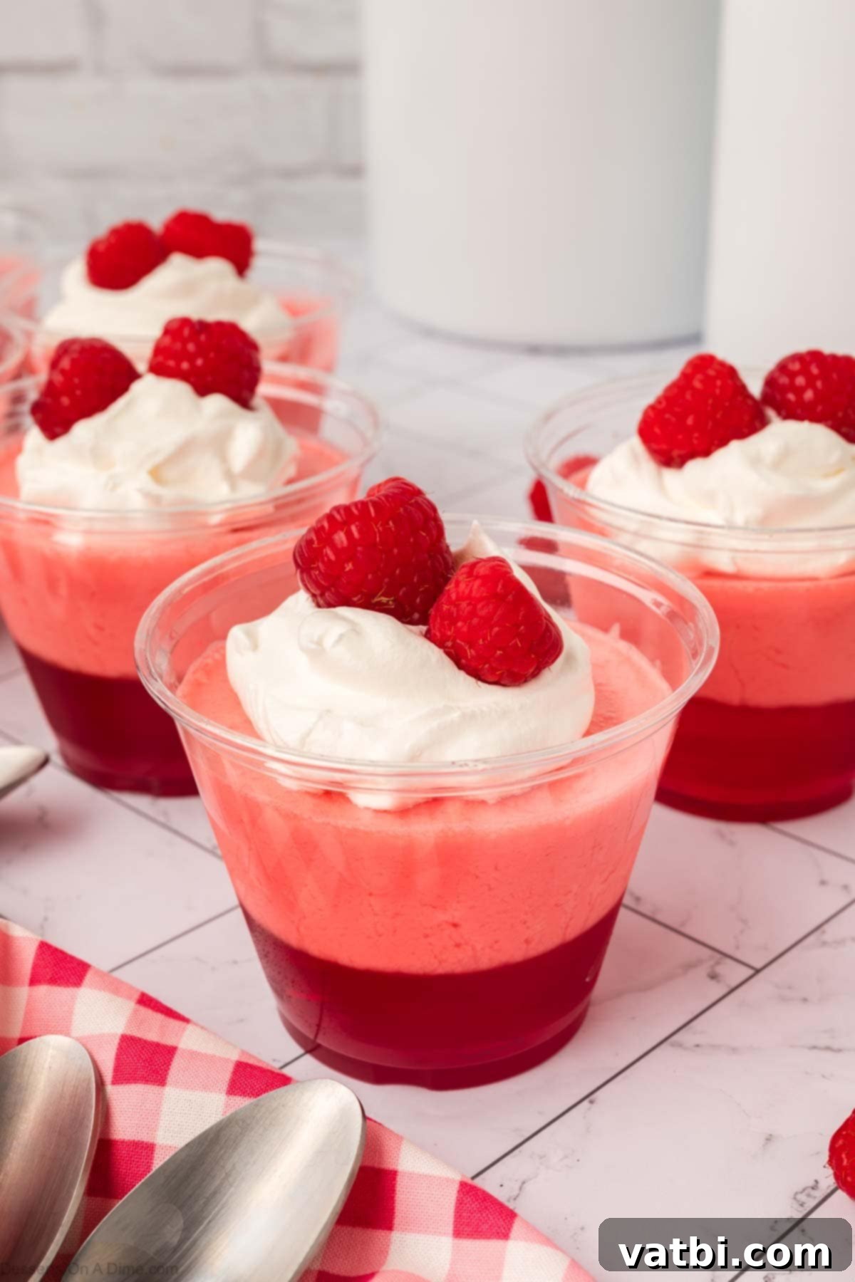 Layered Jello Parfait 12 Finished Jello Parfait with whipped cream and fresh raspberries, ready to be served.