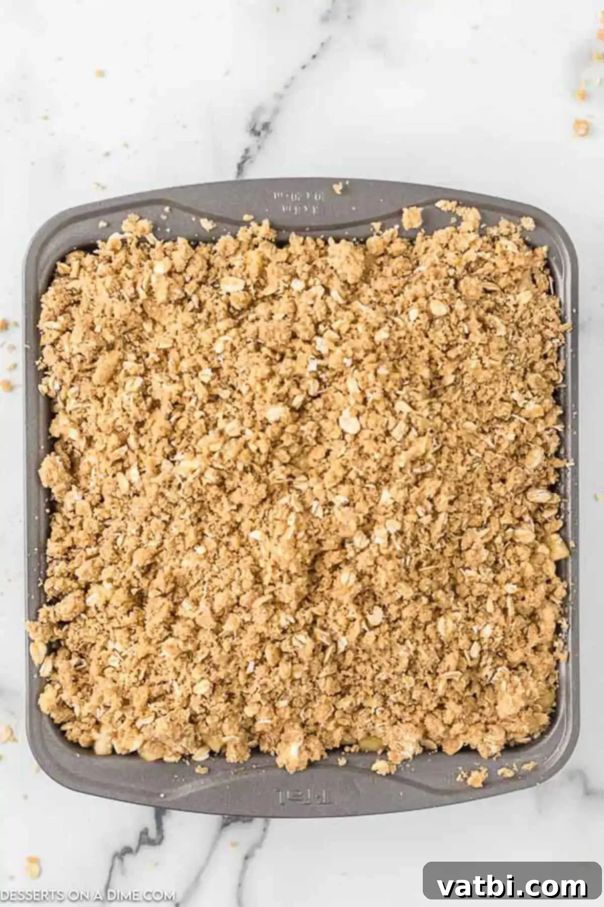 Classic Apple Crisp 9 Topping sprinkled over apple mixture in pan.