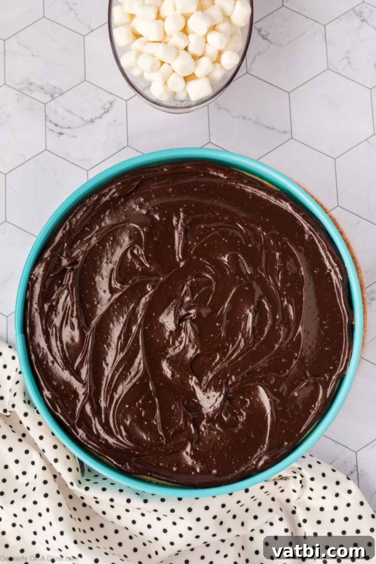 Smores Cheesecake 12 Hot fudge sauce being spread evenly over the cooled cheesecake.