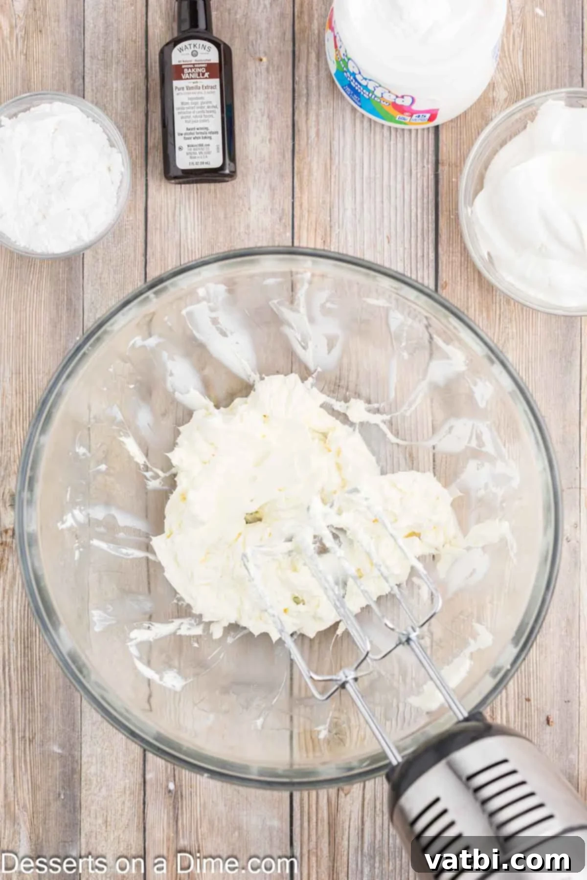 Creamy Cherry Dream Dip 4 An electric hand mixer beating softened cream cheese in a large glass bowl on medium speed until it's smooth and airy.