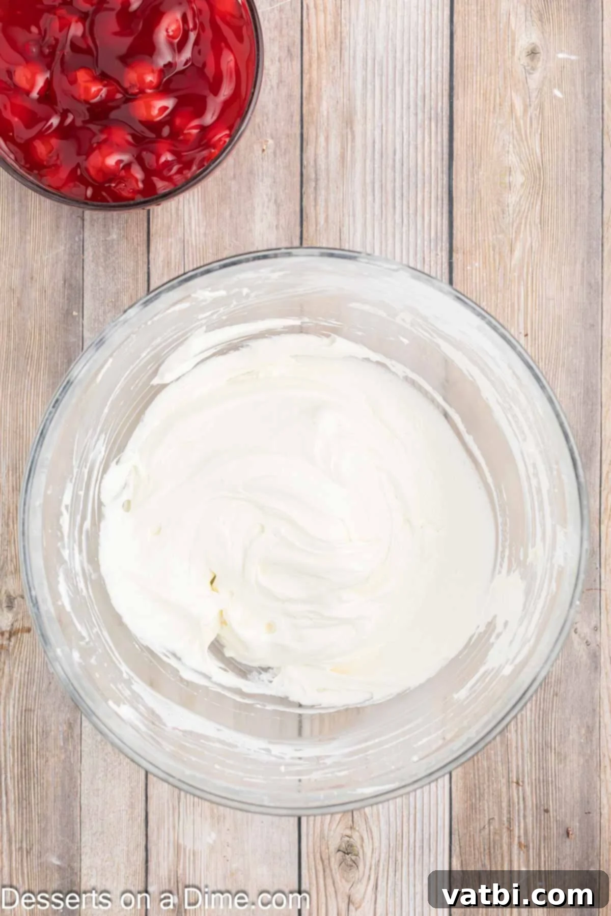 Creamy Cherry Dream Dip 6 Marshmallow creme being gently folded into the cream cheese mixture by hand using a spatula, followed by whipped topping.