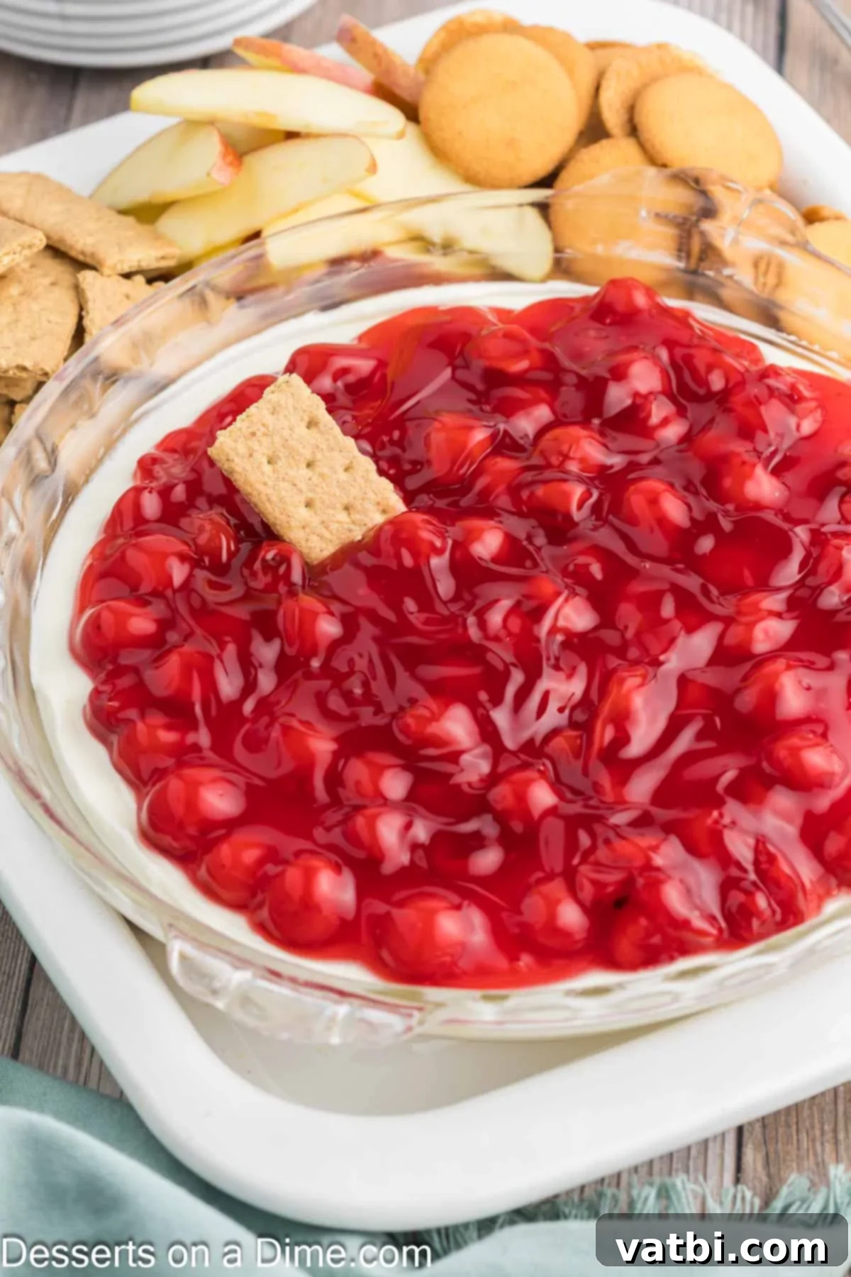 Creamy Cherry Dream Dip 8 Close-up view of the smooth, creamy white cheesecake base layered with a rich, vibrant red cherry pie filling, presented in a glass serving dish.