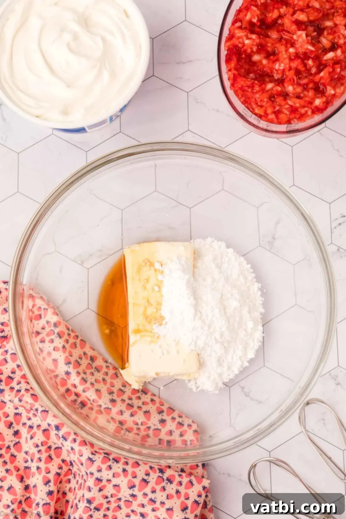 Cream cheese, powdered sugar, and vanilla extract in a bowl, ready to be beaten until smooth and fluffy.