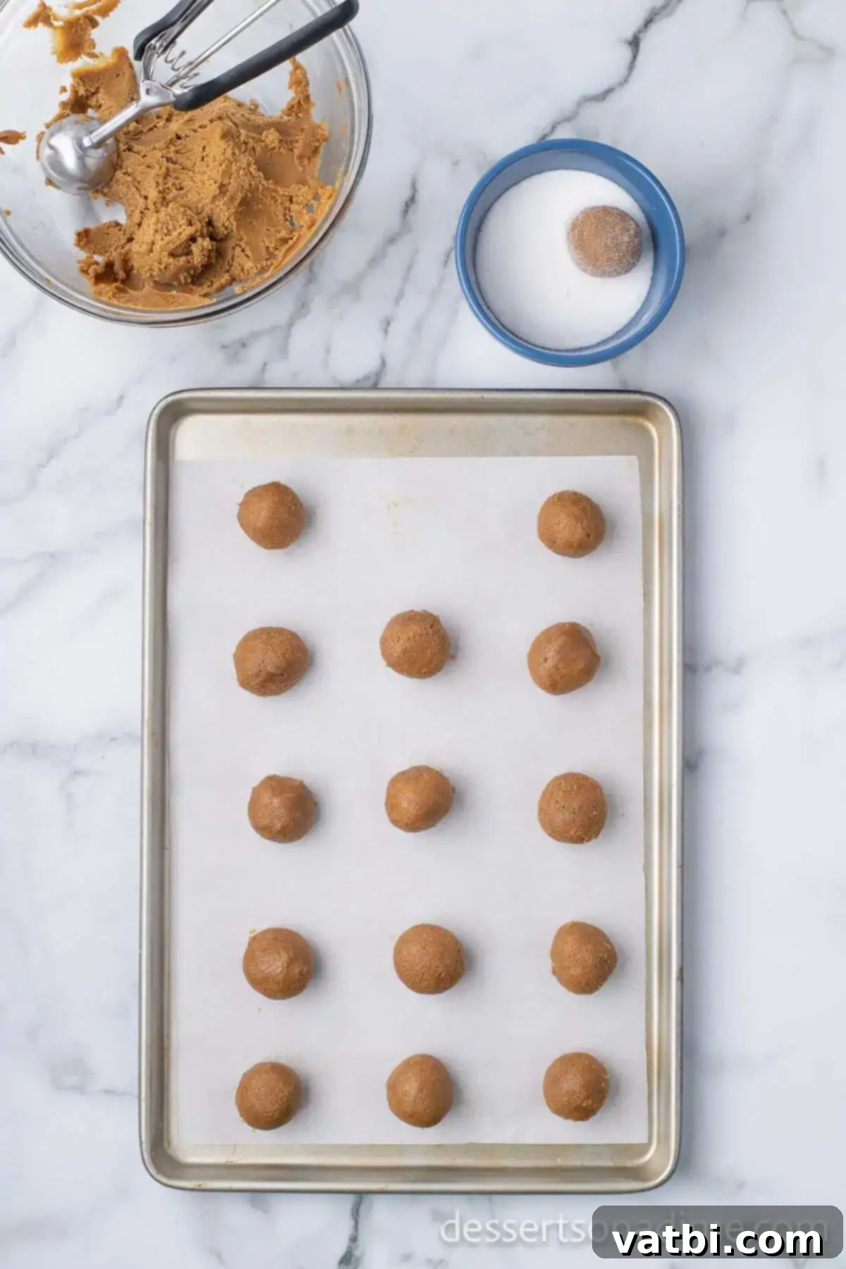 Chewy Ginger Molasses Cookies 9 Scooped cookie dough balls, some coated in sugar, arranged on a baking sheet lined with parchment paper.