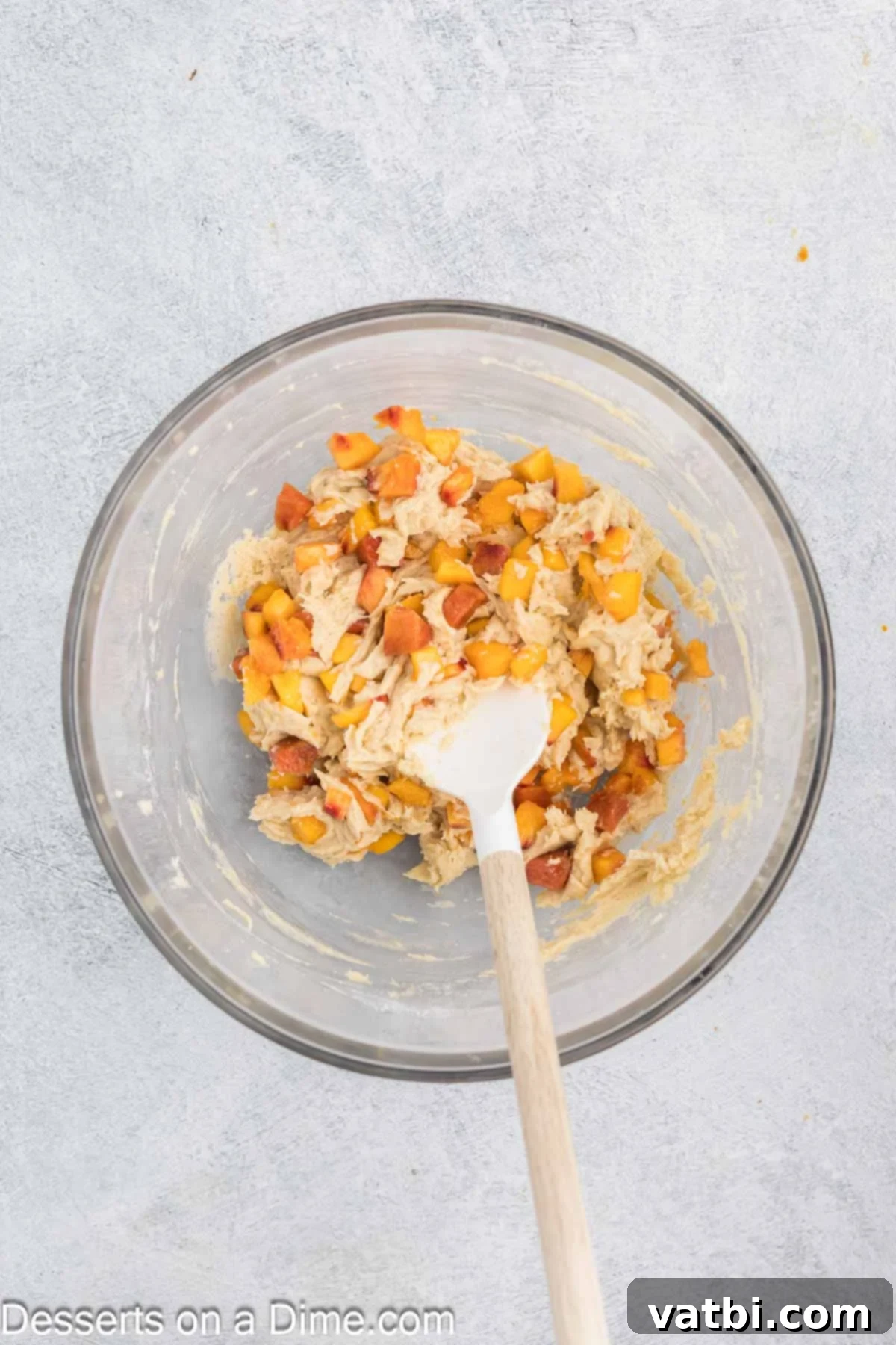 Wet and dry ingredients combined together with peaches folded in, showing a thick batter.