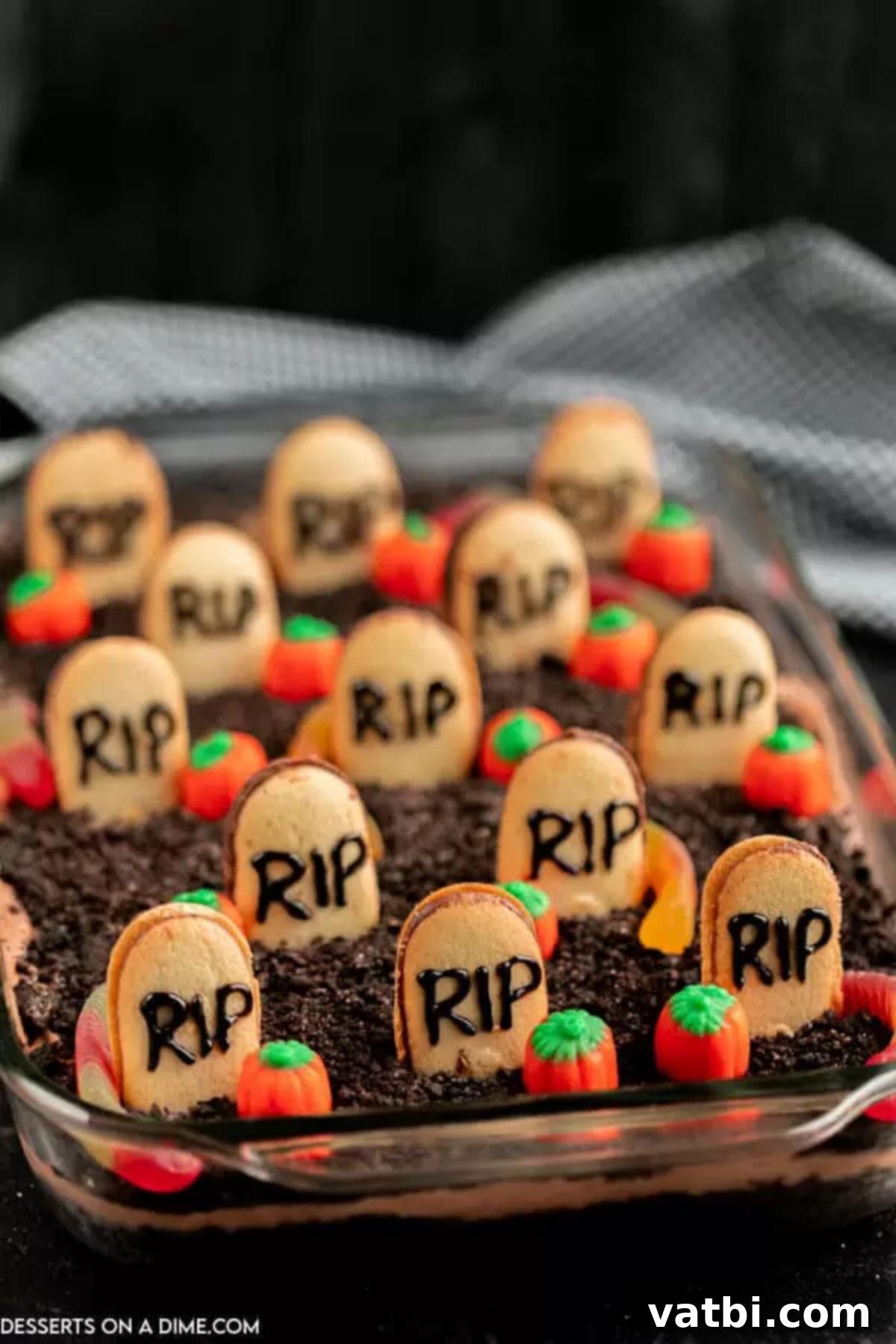 Spooky Halloween Dirt Cake 4 A baking dish filled with Halloween Dirt Cake, showing the distinct layers of crushed Oreos and chocolate pudding, with a hint of tombstones and gummy worms peeking out.