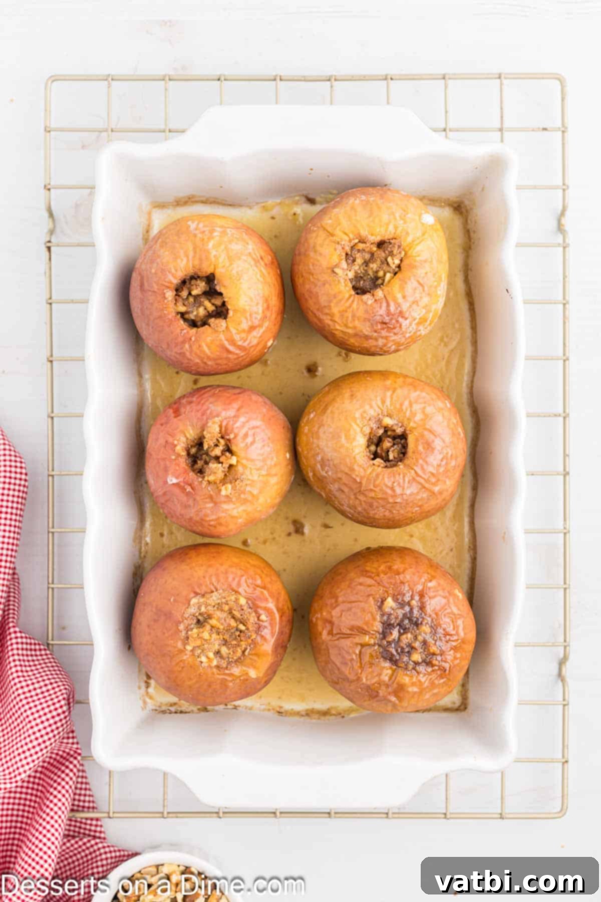 Warm Spiced Baked Apples 6 Freshly baked apples cooling in the baking dish, their skins slightly wrinkled and softened, with the caramelized filling bubbling warmly in the centers.