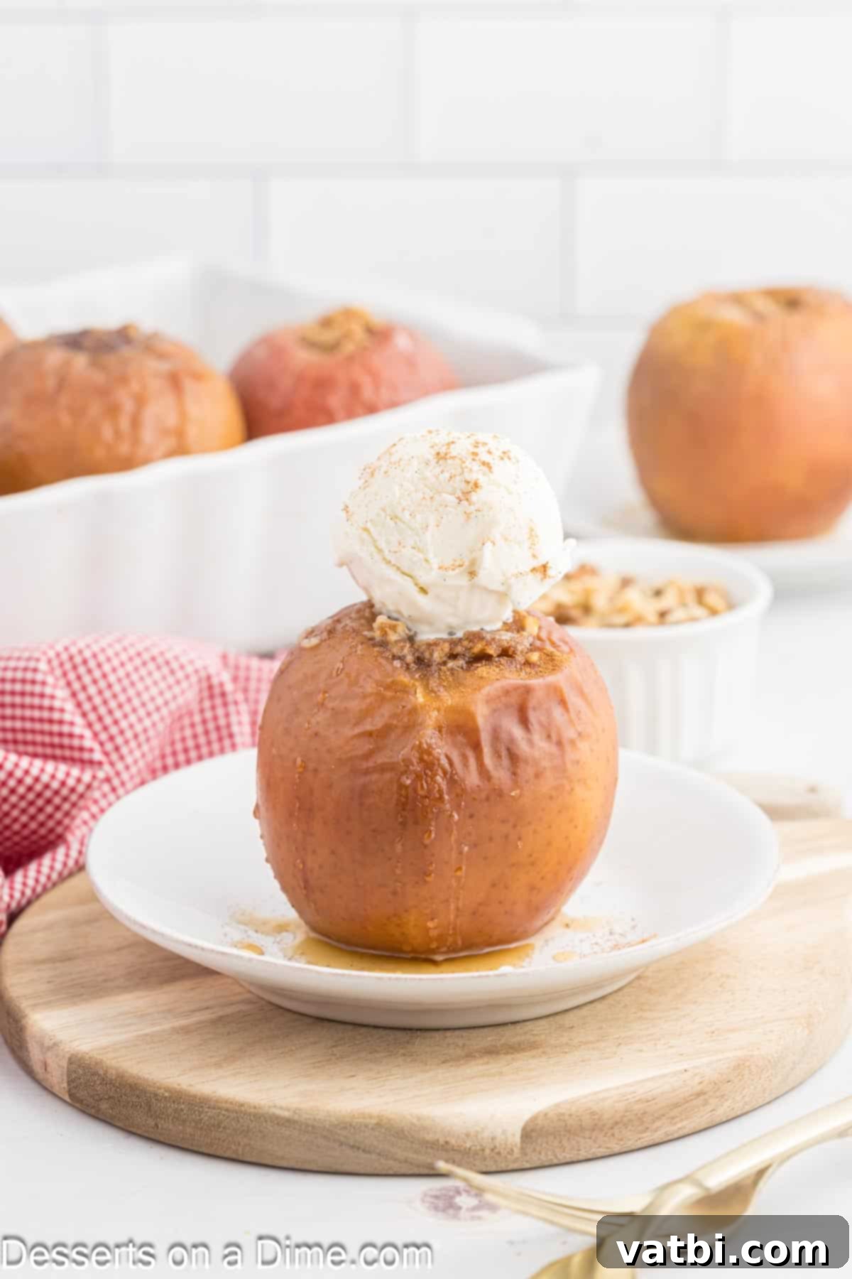 Warm Spiced Baked Apples 8 Two baked apples served in a shallow white bowl, topped generously with melting vanilla ice cream and a light sprinkle of cinnamon, presenting a comforting and inviting dessert.