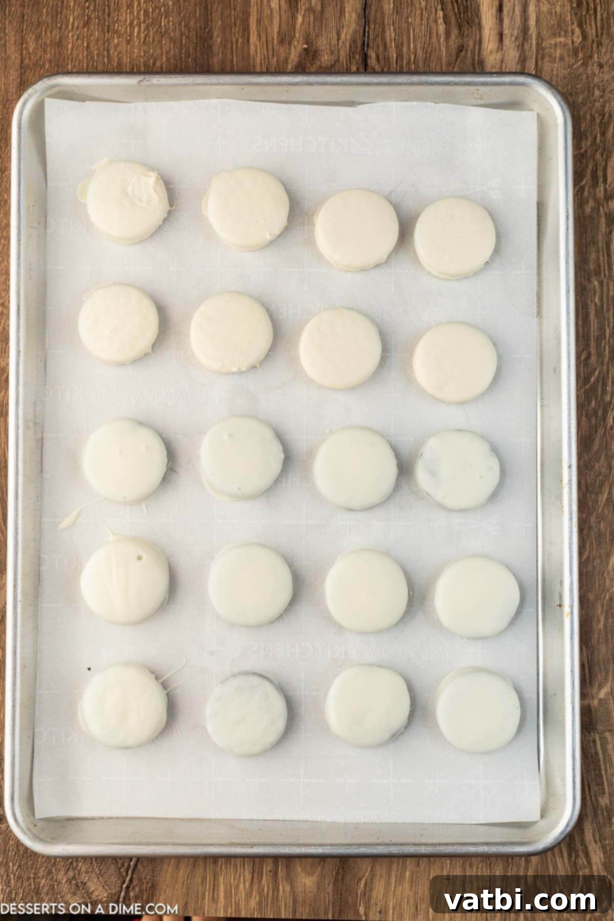 Decadent White Chocolate Oreos 4 White chocolate covered Oreos neatly arranged on a wax paper lined baking sheet.