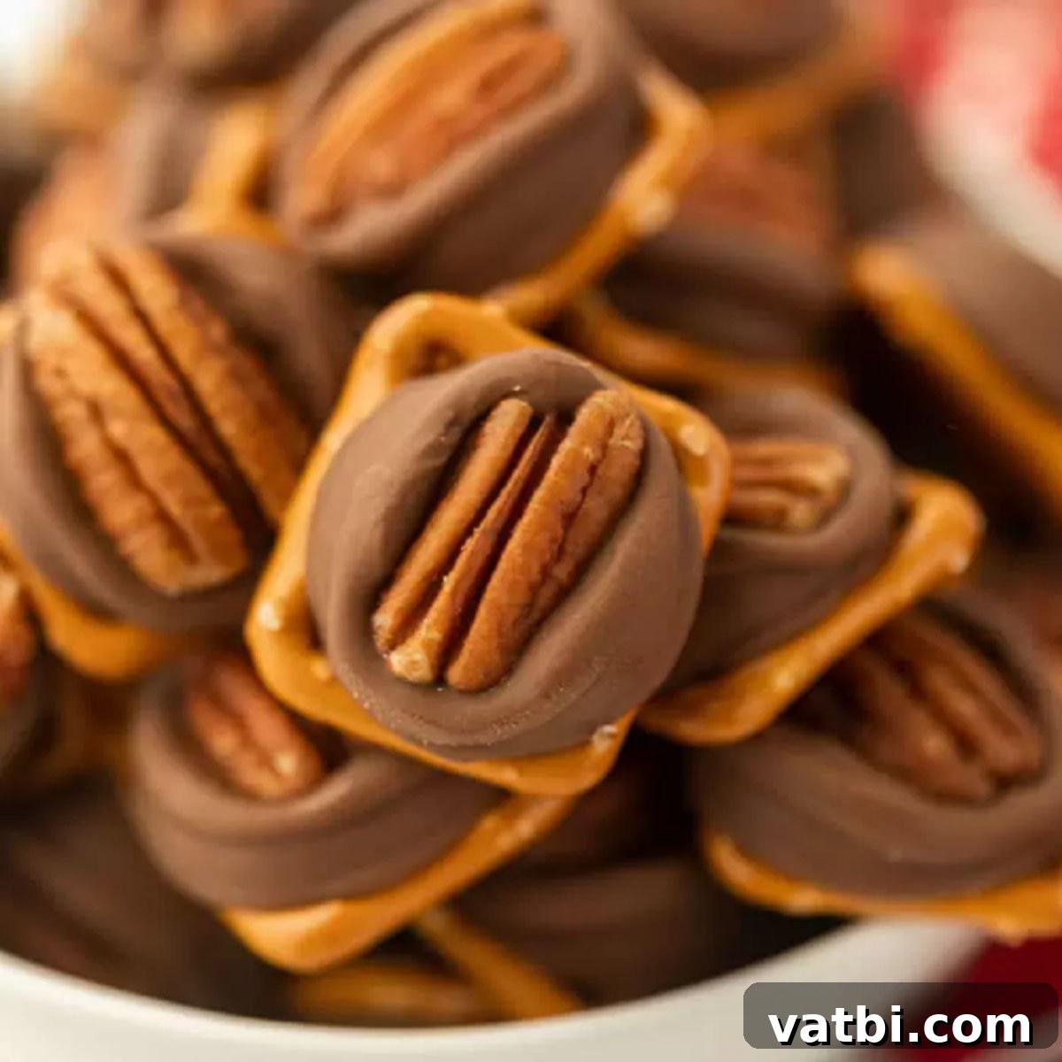 A close-up shot of a bowl filled with Rolo Pretzel Turtles, showcasing the glistening chocolate and perfect pecan halves.