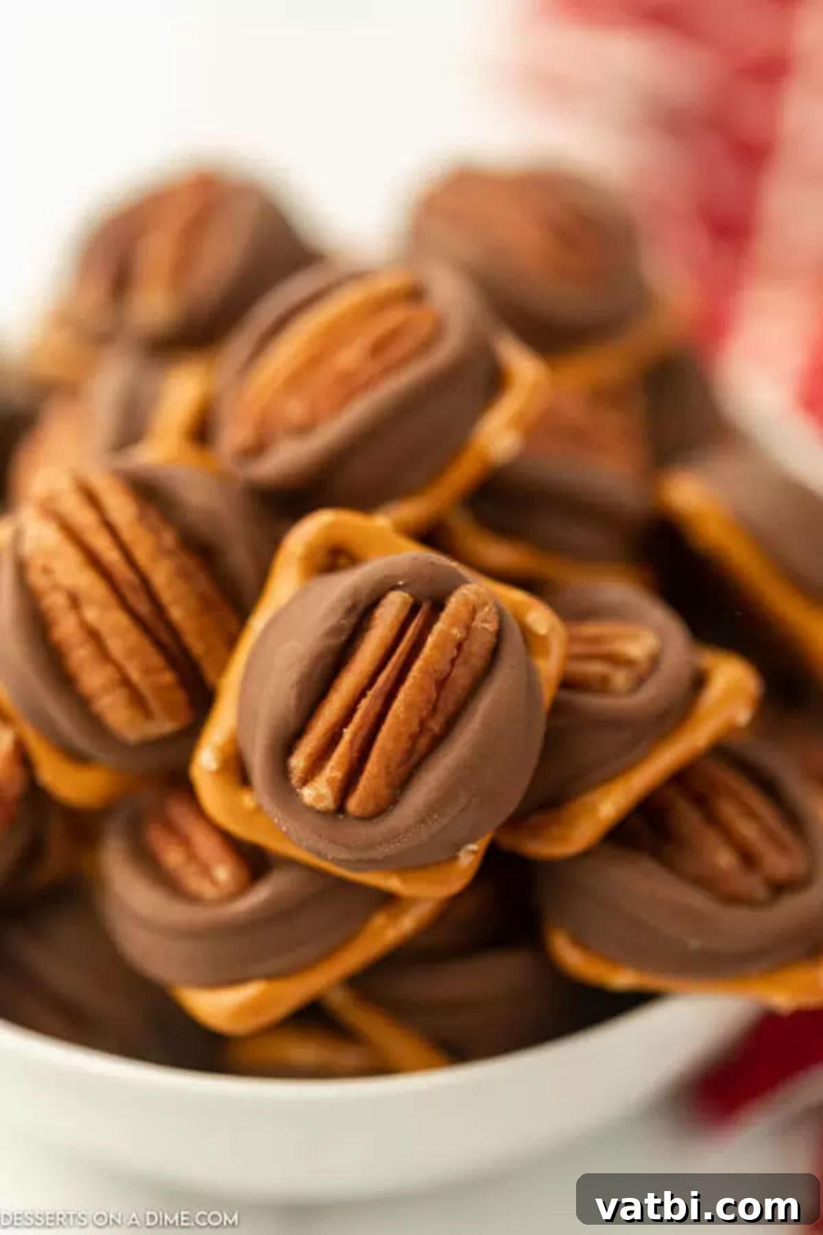 A small stack of Rolo Pretzel Turtles in a bowl, showing the intricate layers of pretzel, melted Rolo, and pecan.