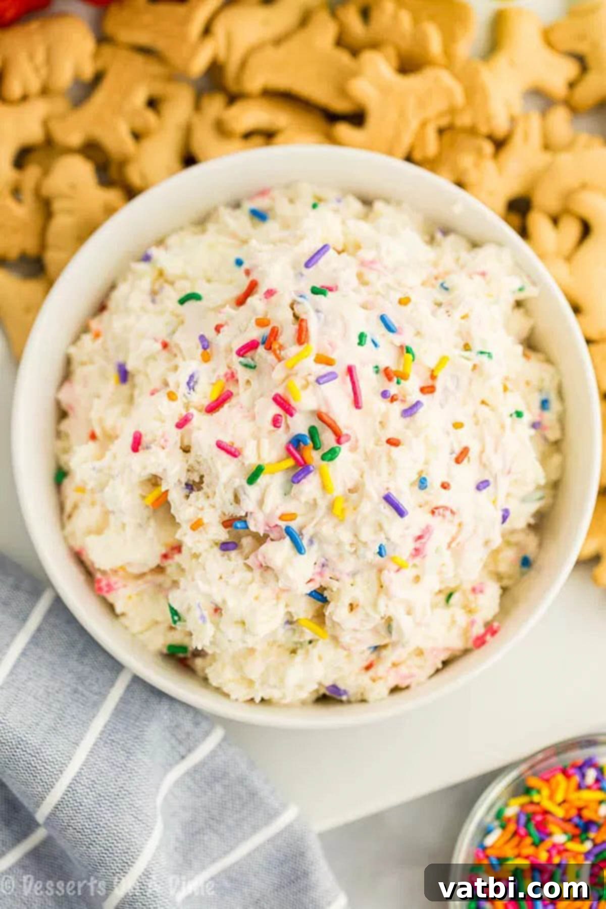 You only need 4 ingredients to make this decadent Cake Batter Dip Recipe. Serve it with fruit, graham crackers or anything you like for an amazing treat. A beautifully presented bowl of Cake Batter Dip, garnished with colorful sprinkles, ready to be served at a party.