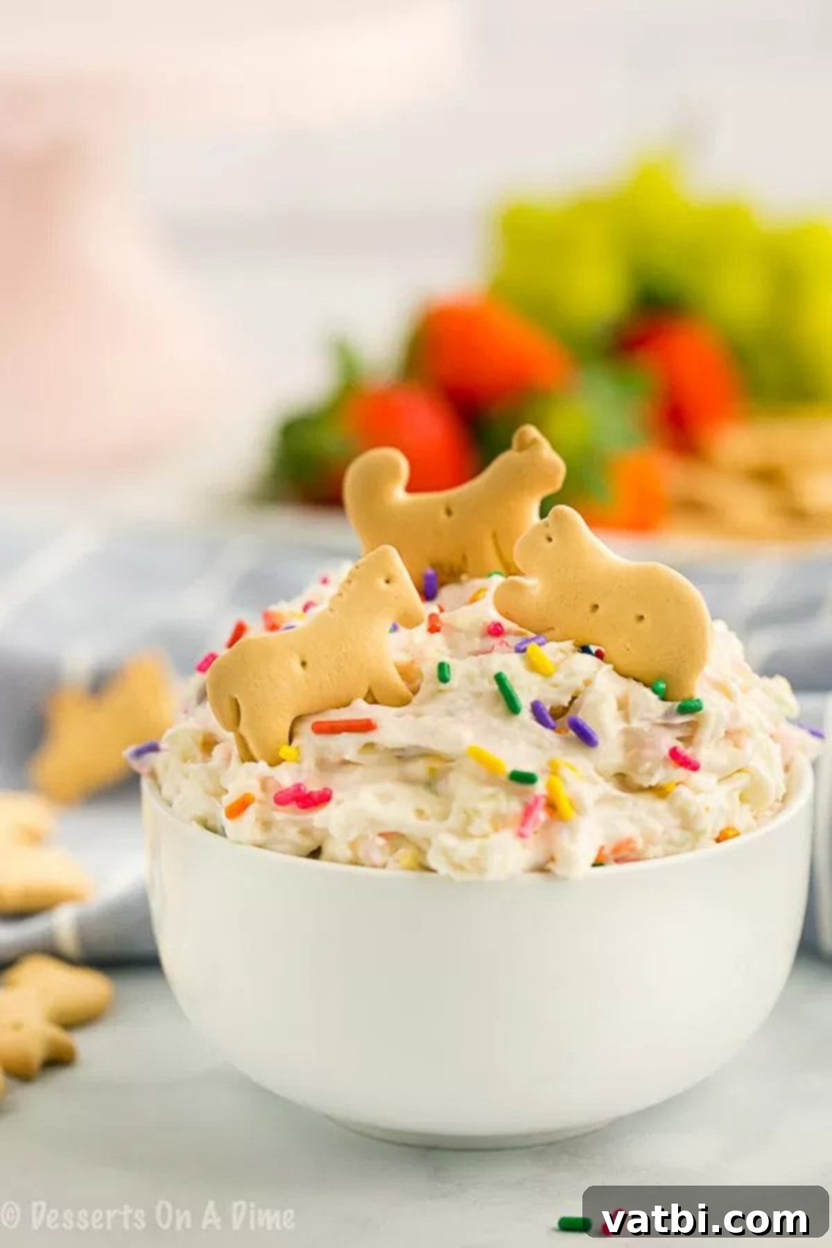 You only need 4 ingredients to make this decadent Cake Batter Dip Recipe. Serve it with fruit, graham crackers or anything you like for an amazing treat. A festive serving bowl of Cake Batter Dip, with animal crackers artfully arranged around the edges, ready for a party.