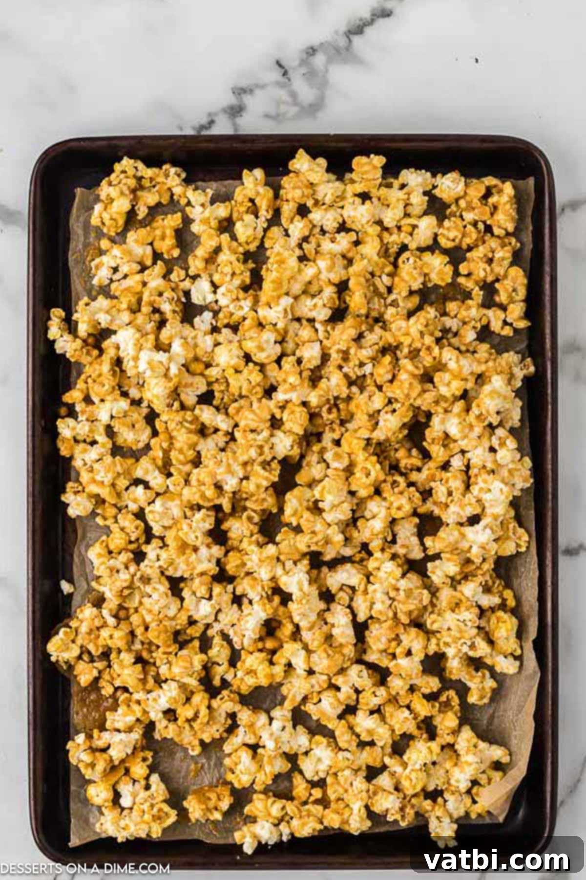 Ultimate Caramel Popcorn 7 Popcorn spread on baking sheets.