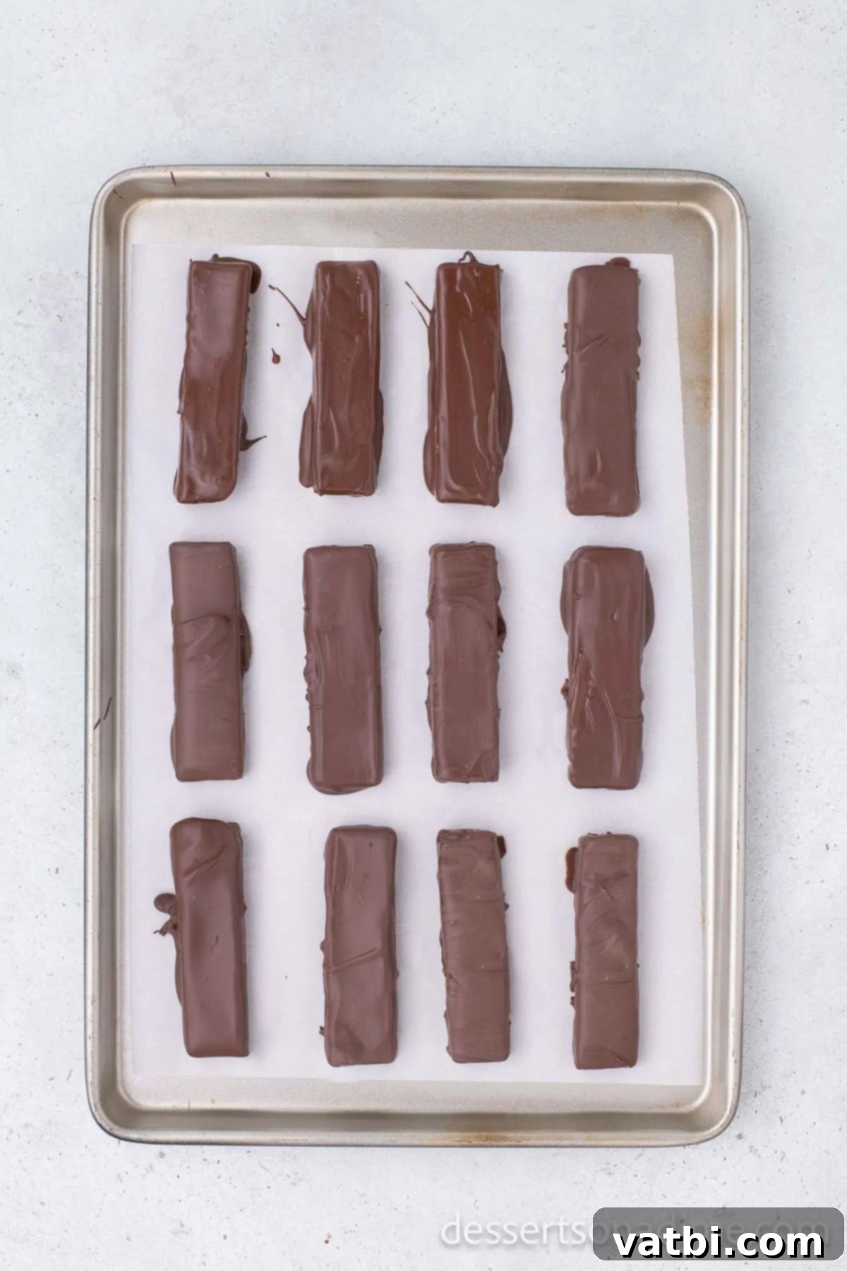 DIY Butterfinger Bars 7 Homemade Butterfinger bars coated in melted chocolate and placed on a baking sheet lined with parchment paper to set.