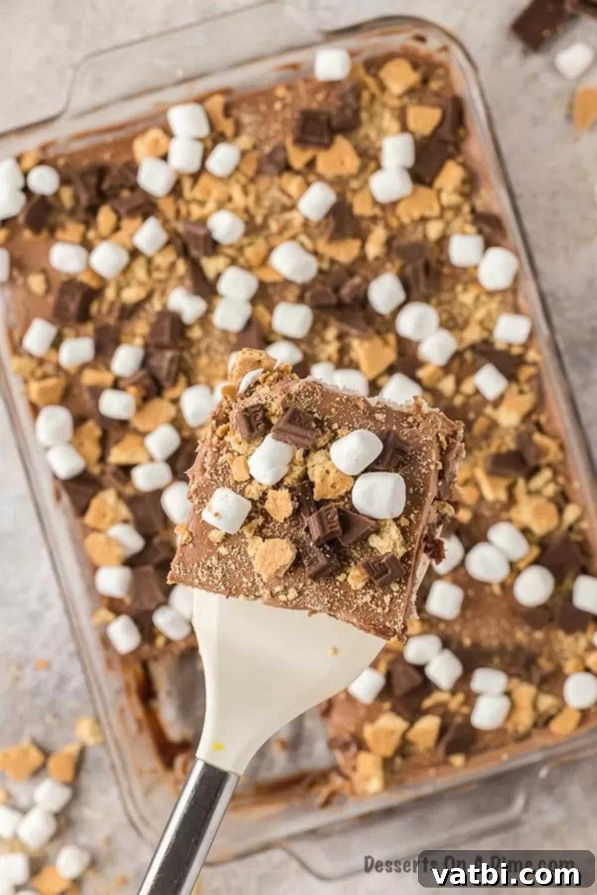 Smores poke cake topped with marshmallows, chocolate and graham crackers.