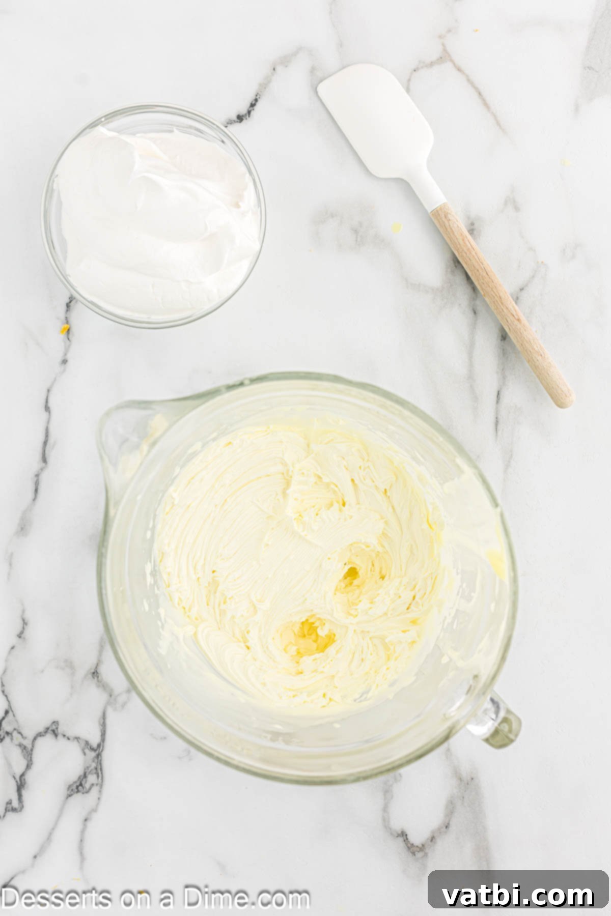 Tangy Lemon Infusion Cake 8 Lemon frosting being beaten with a hand mixer in a bowl until light and fluffy.