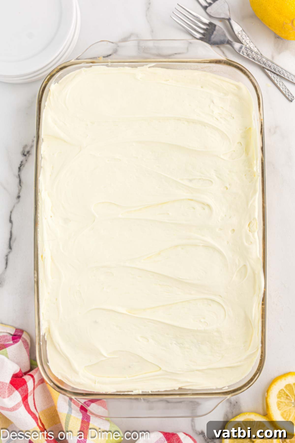 Tangy Lemon Infusion Cake 9 The light and fluffy lemon-whipped topping mixture being spread evenly over the chilled lemon poke cake.