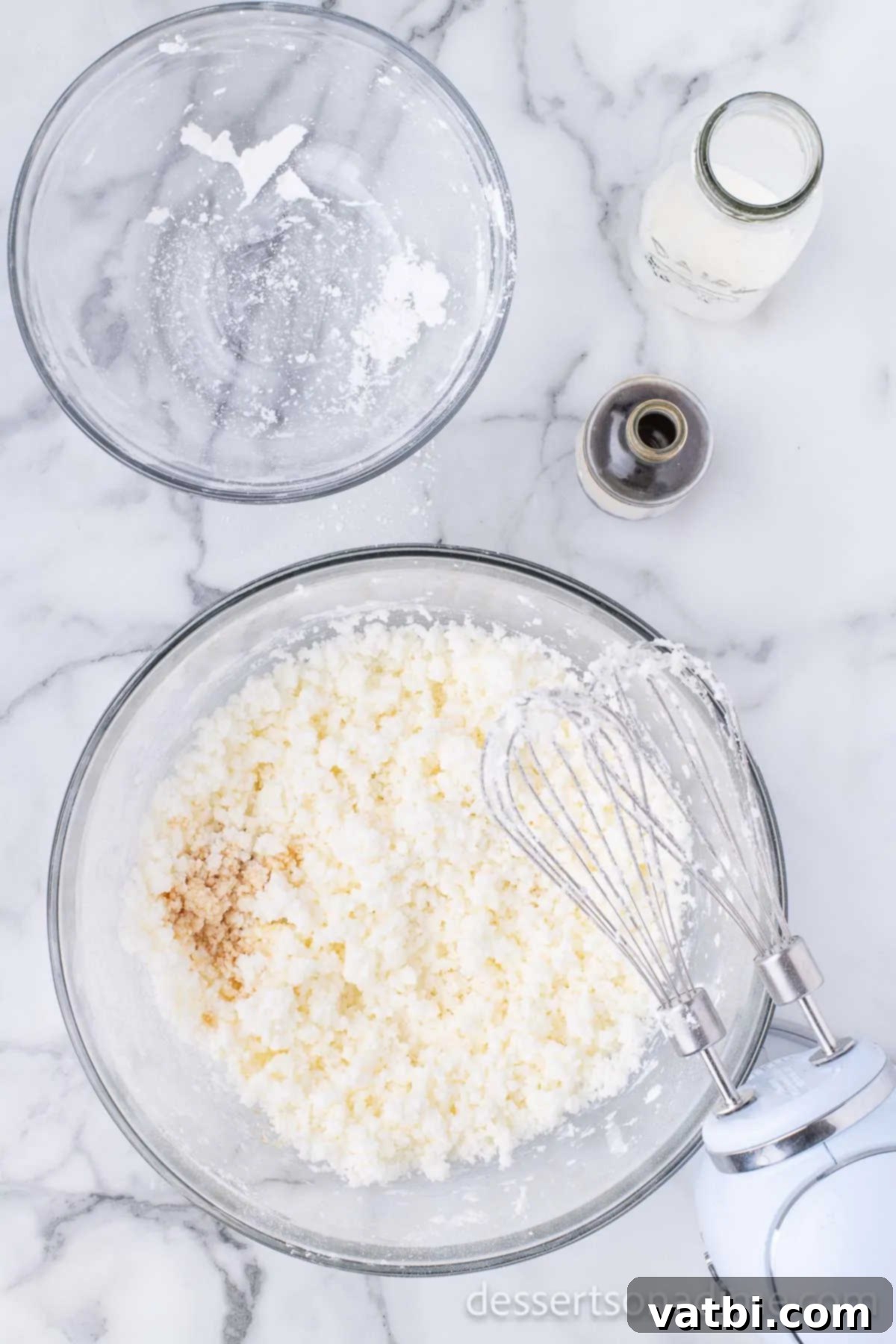 Vanilla extract being added to the frosting mixture in a mixing bowl.