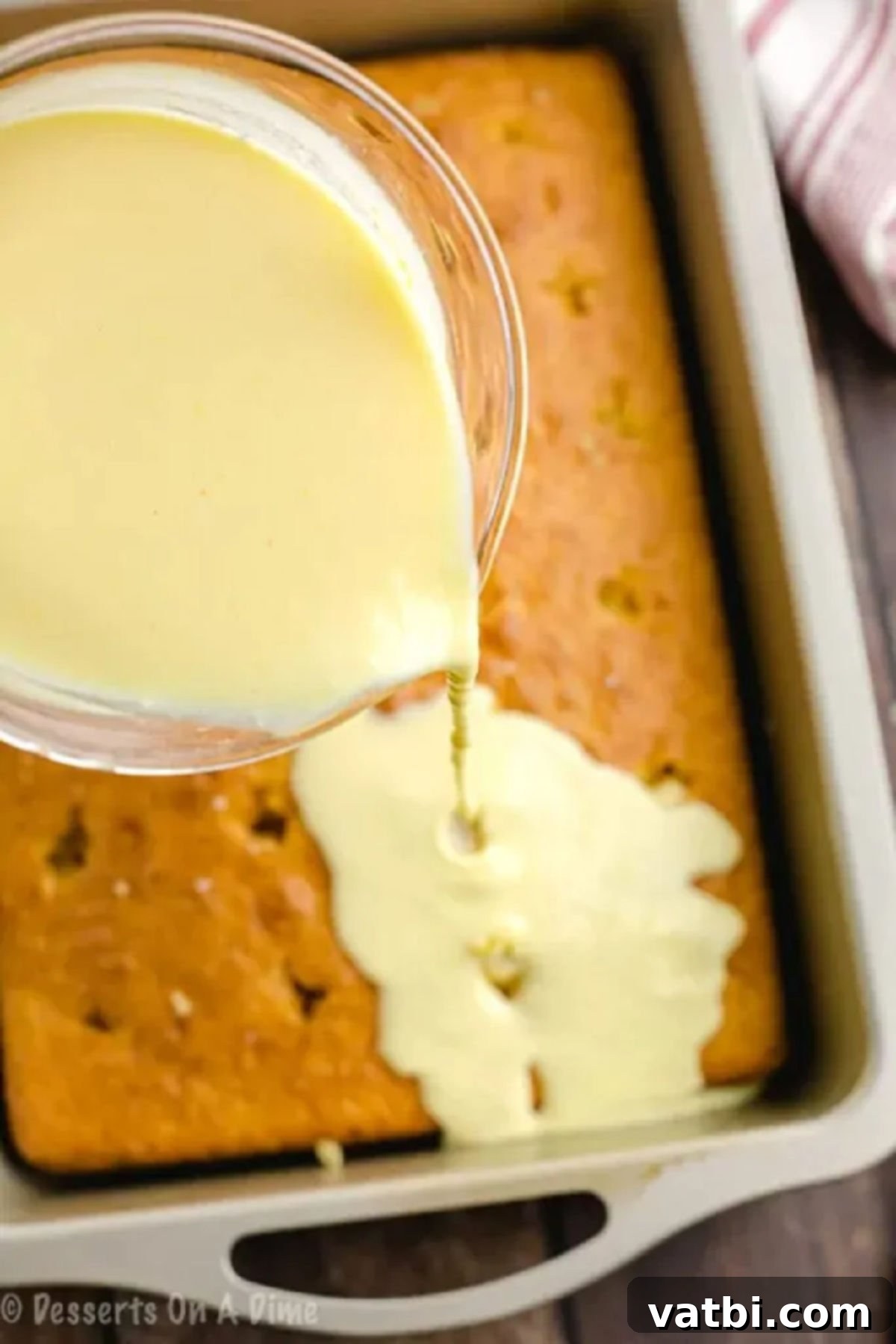 Boston Cream Poke Cake 2 Vanilla pudding being poured over the poked cake.