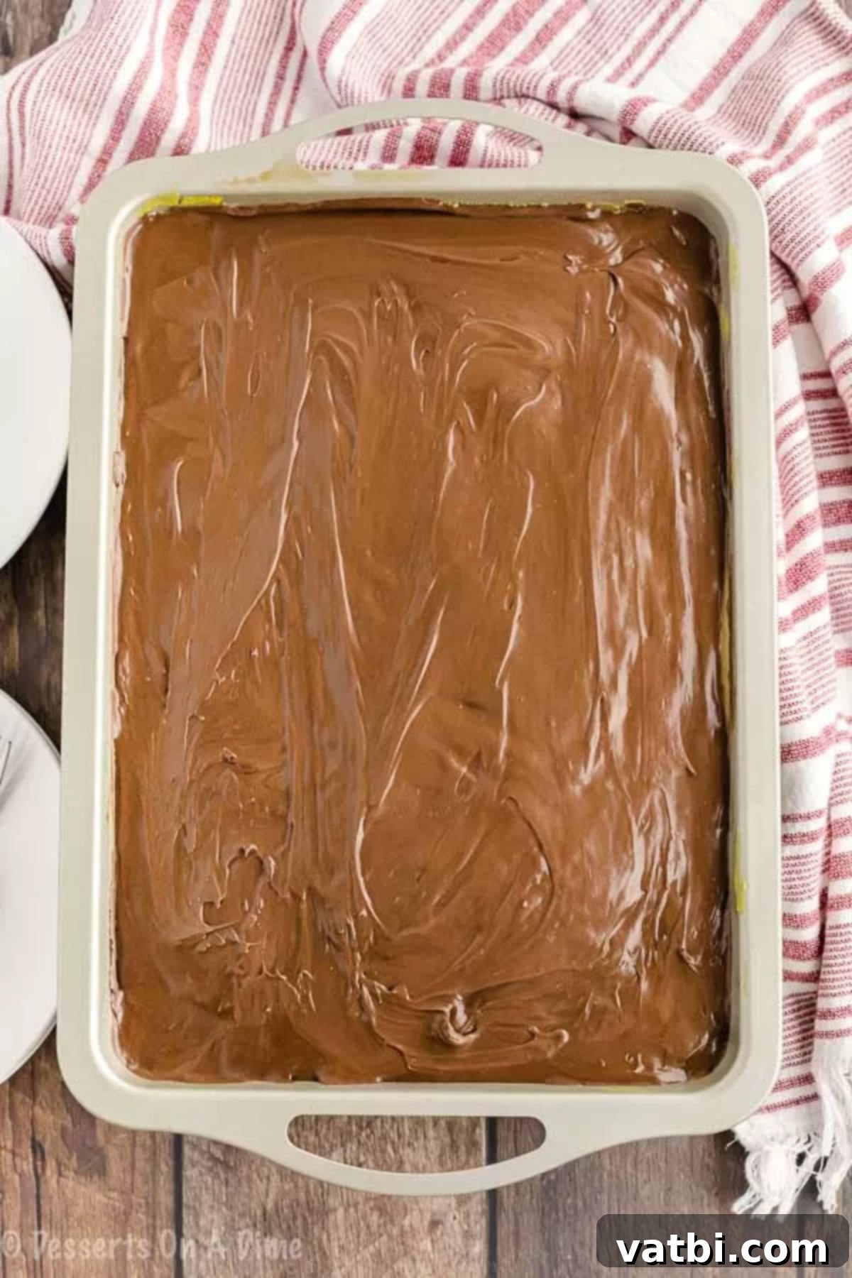Boston Cream Poke Cake 4 Chocolate frosting smoothly spread over the cake, covering the pudding layer.