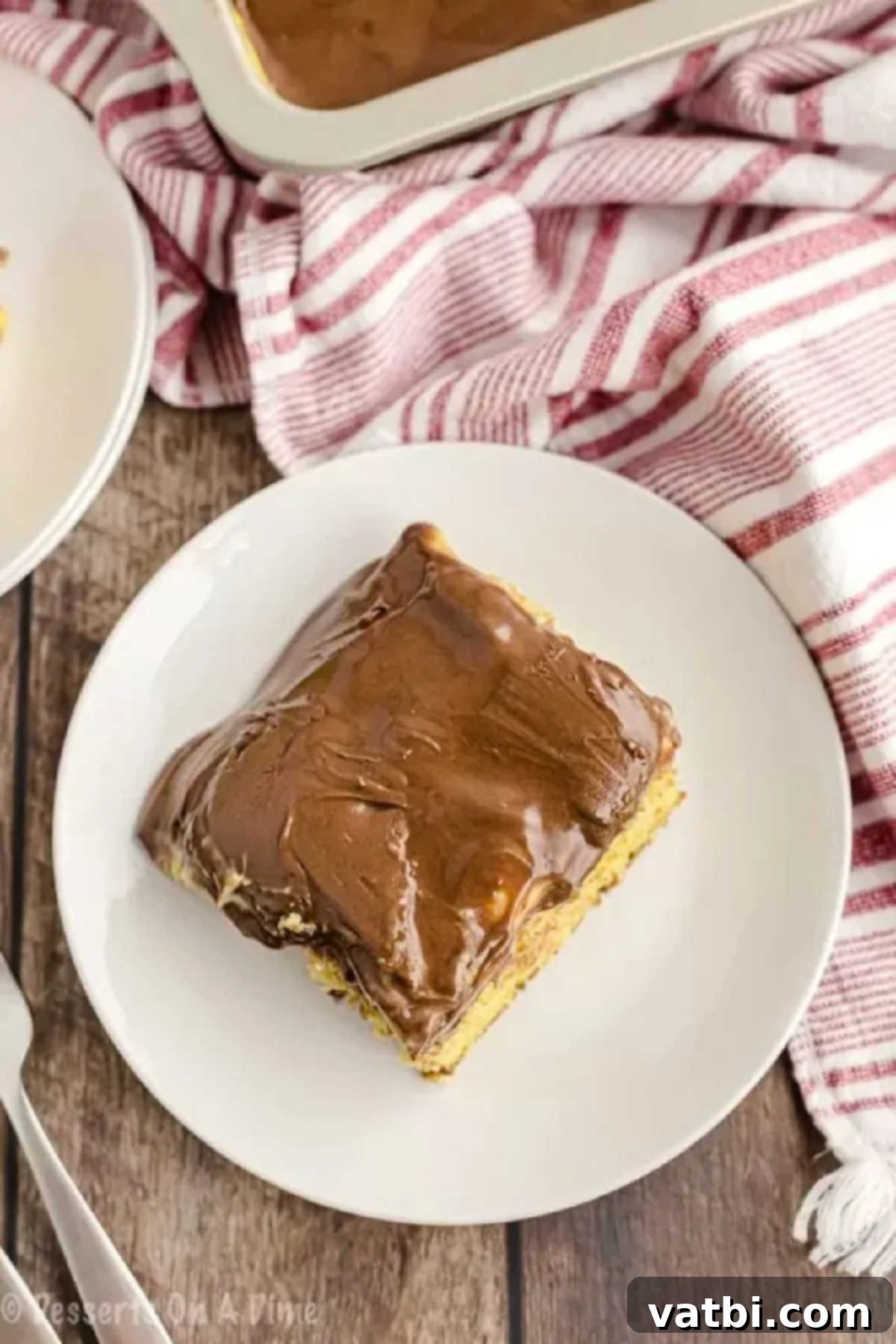 Boston Cream Poke Cake 5 A perfectly sliced piece of Boston Cream Poke Cake ready to be served on a plate.